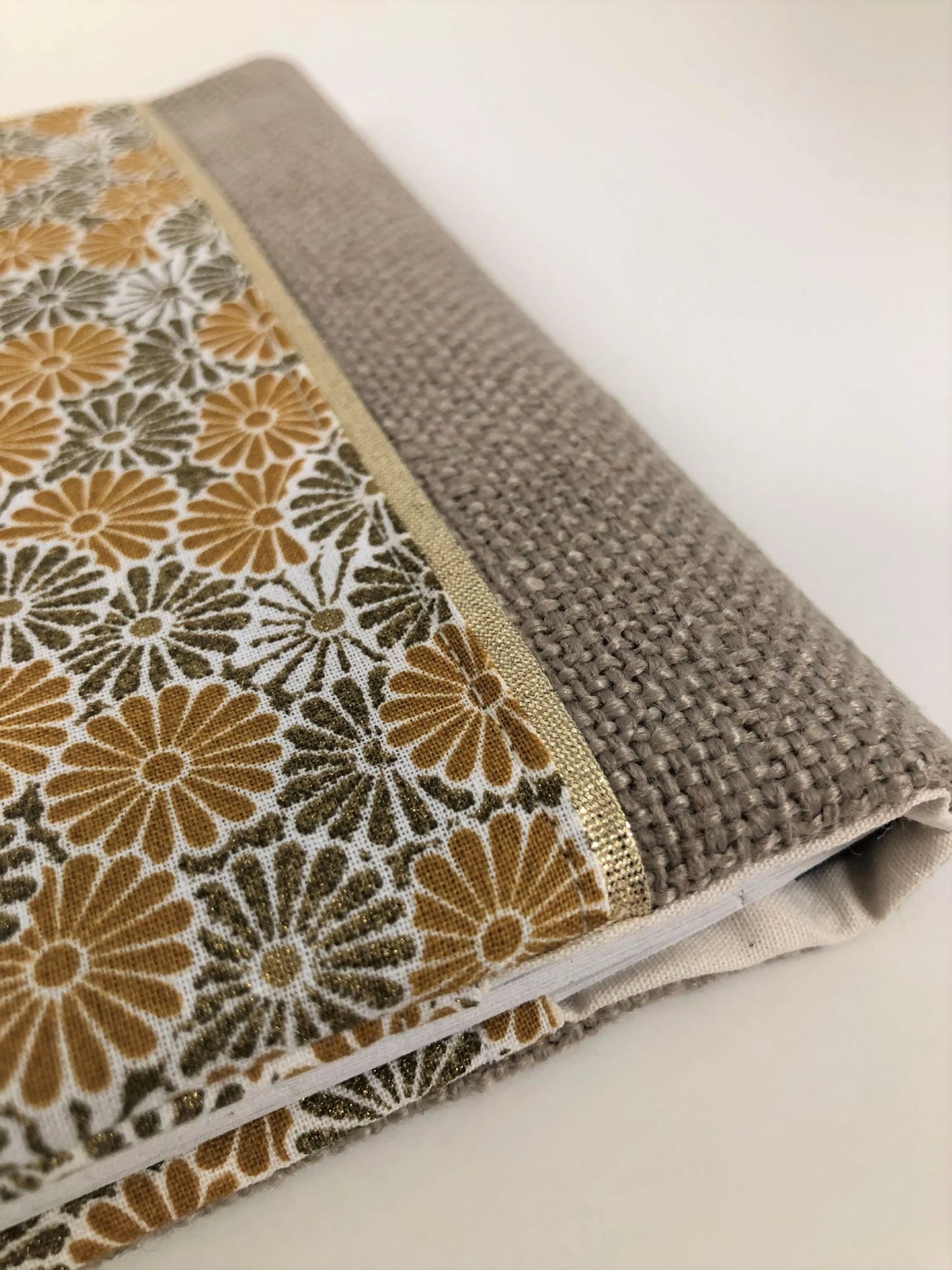 Vue détaillée du porte-chéquier beige à fleurs moutarde et bronze.