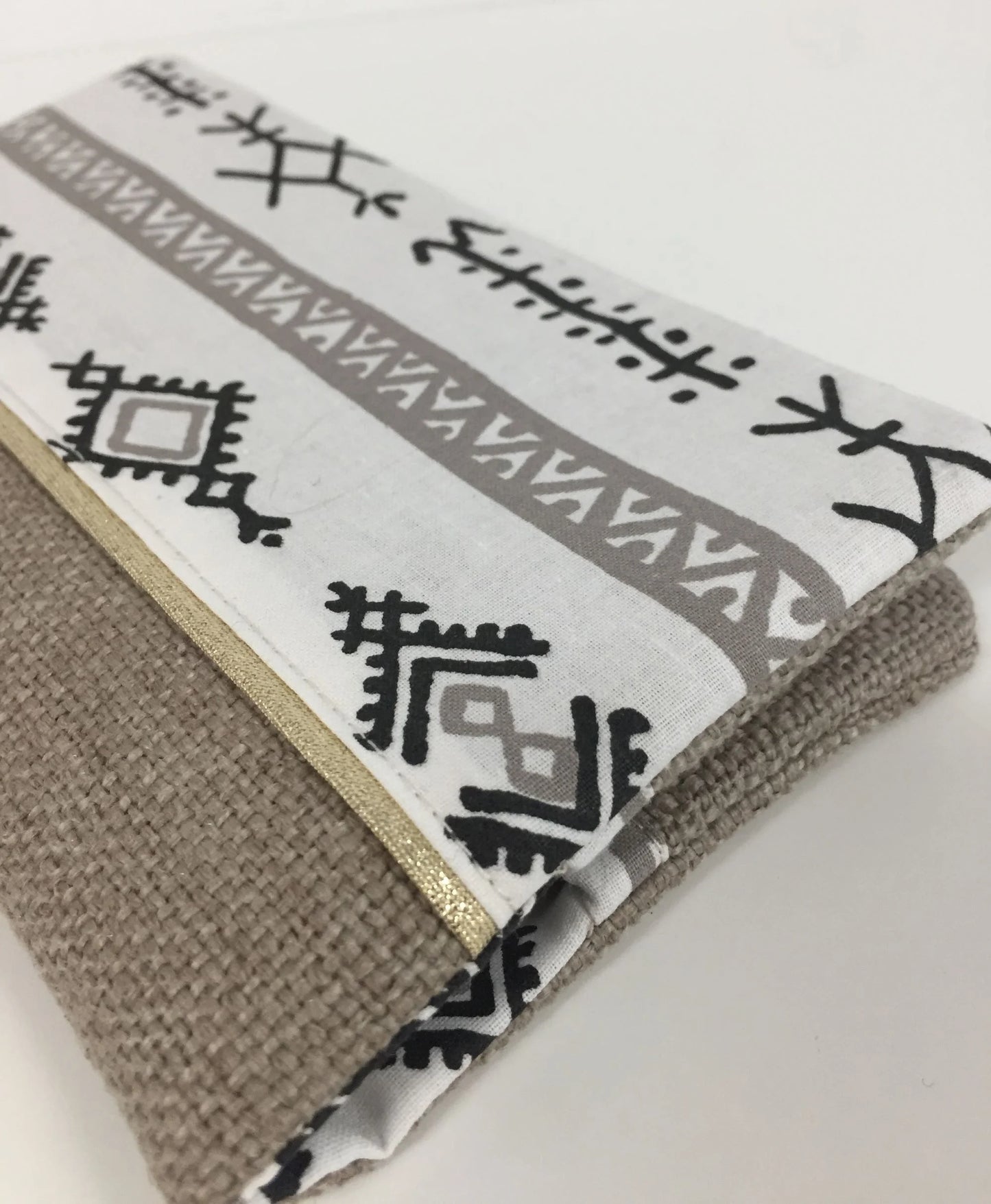 Vue détaillée du tissu ethnique du porte-chéquier ethnique beige, blanc et doré.