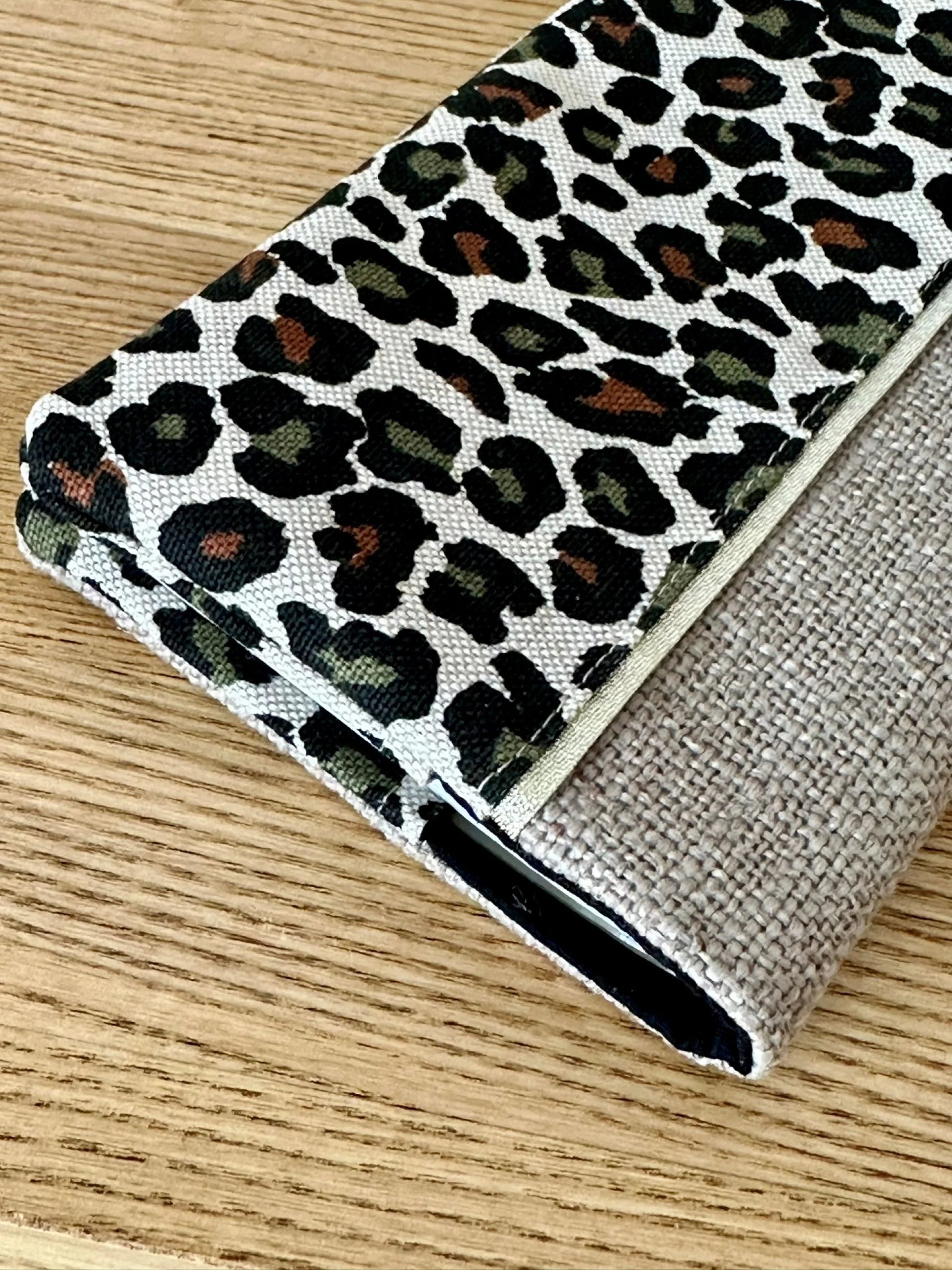 Vue détaillée du porte chéquier léopard en lin beige, avec son liseré doré.