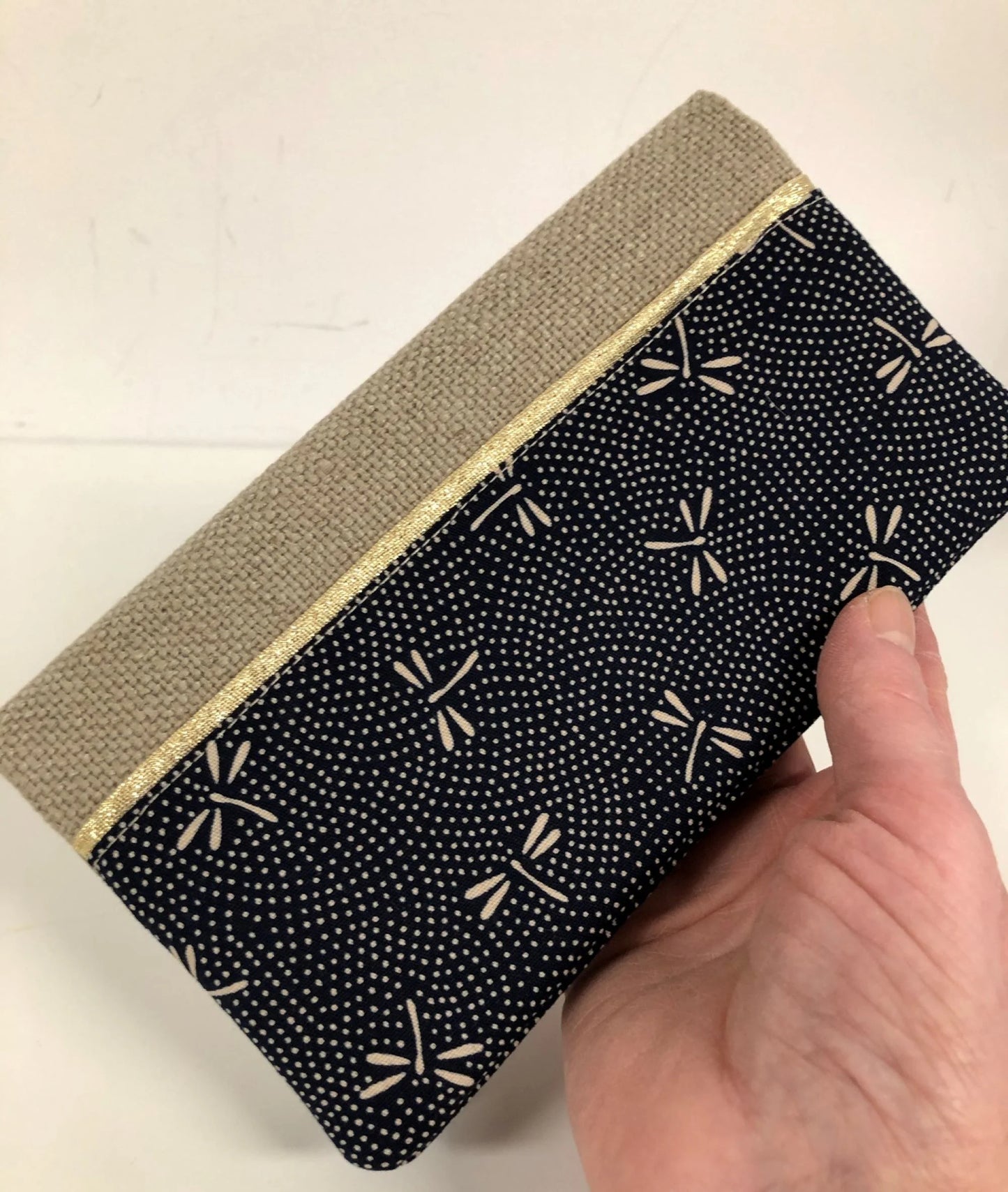 Le porte chéquier en lin beige et tissu japonais bleu libellules tenu en main