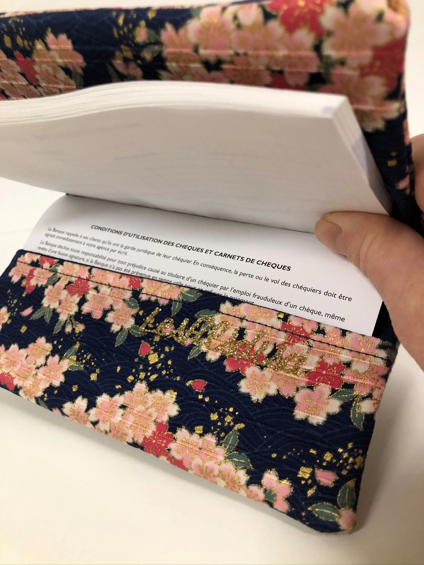 Le rabat inférieur du porte-chéquier en lin beige et tissu japonais fleuri Sakura.