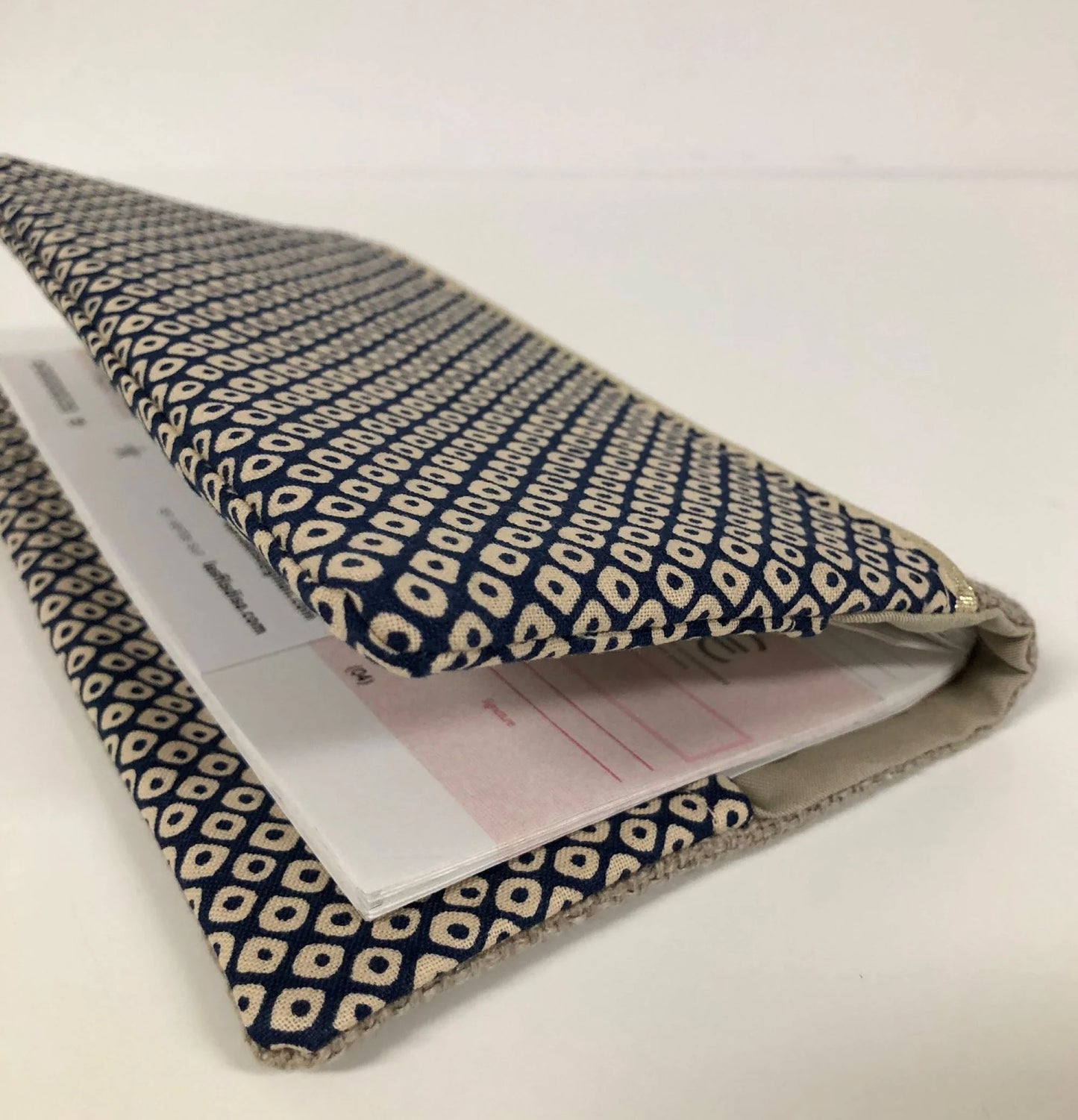 Chéquier installé dans le porte-chéquier en lin beige et tissu japonais Shibori bleu.