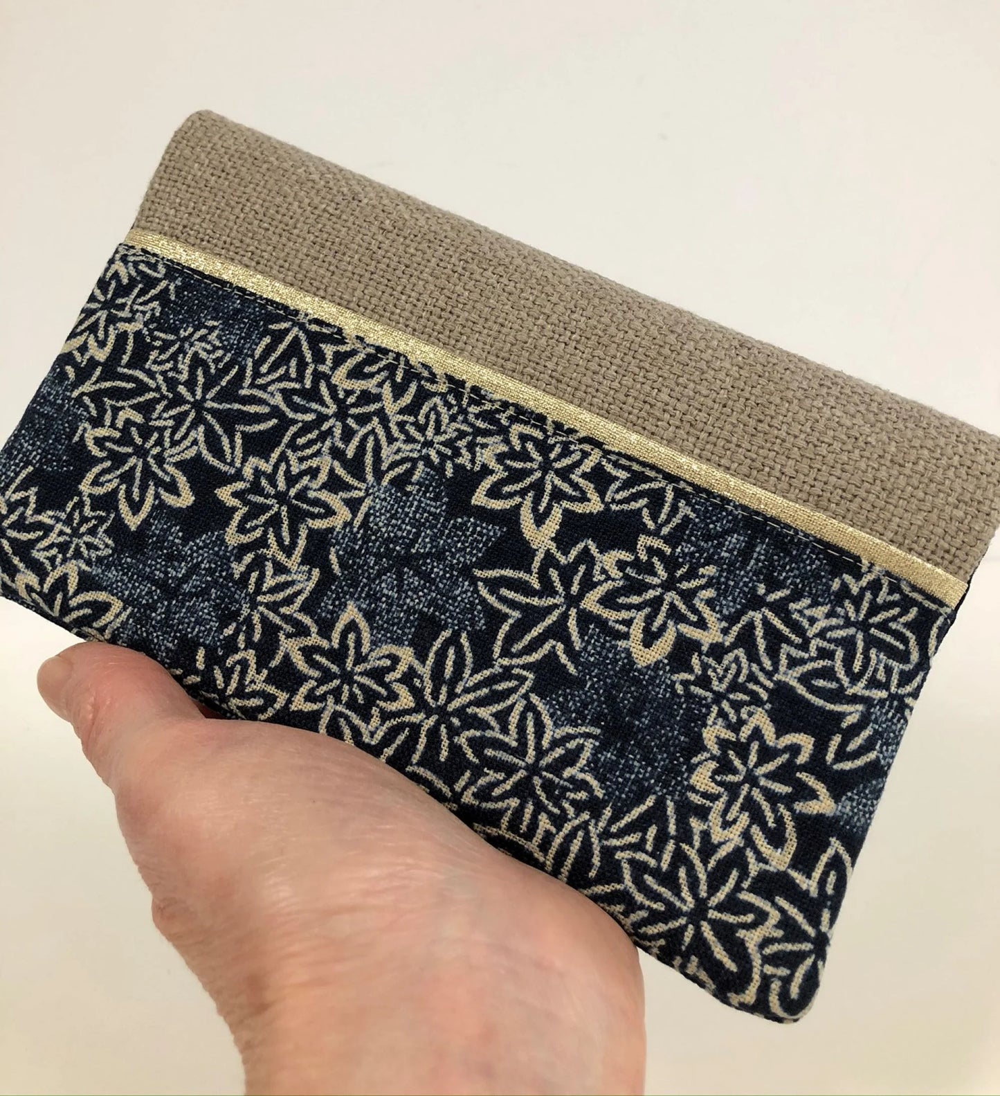 Le porte chéquier en lin et tissu japonais traditionnel bleu, tenu en main.