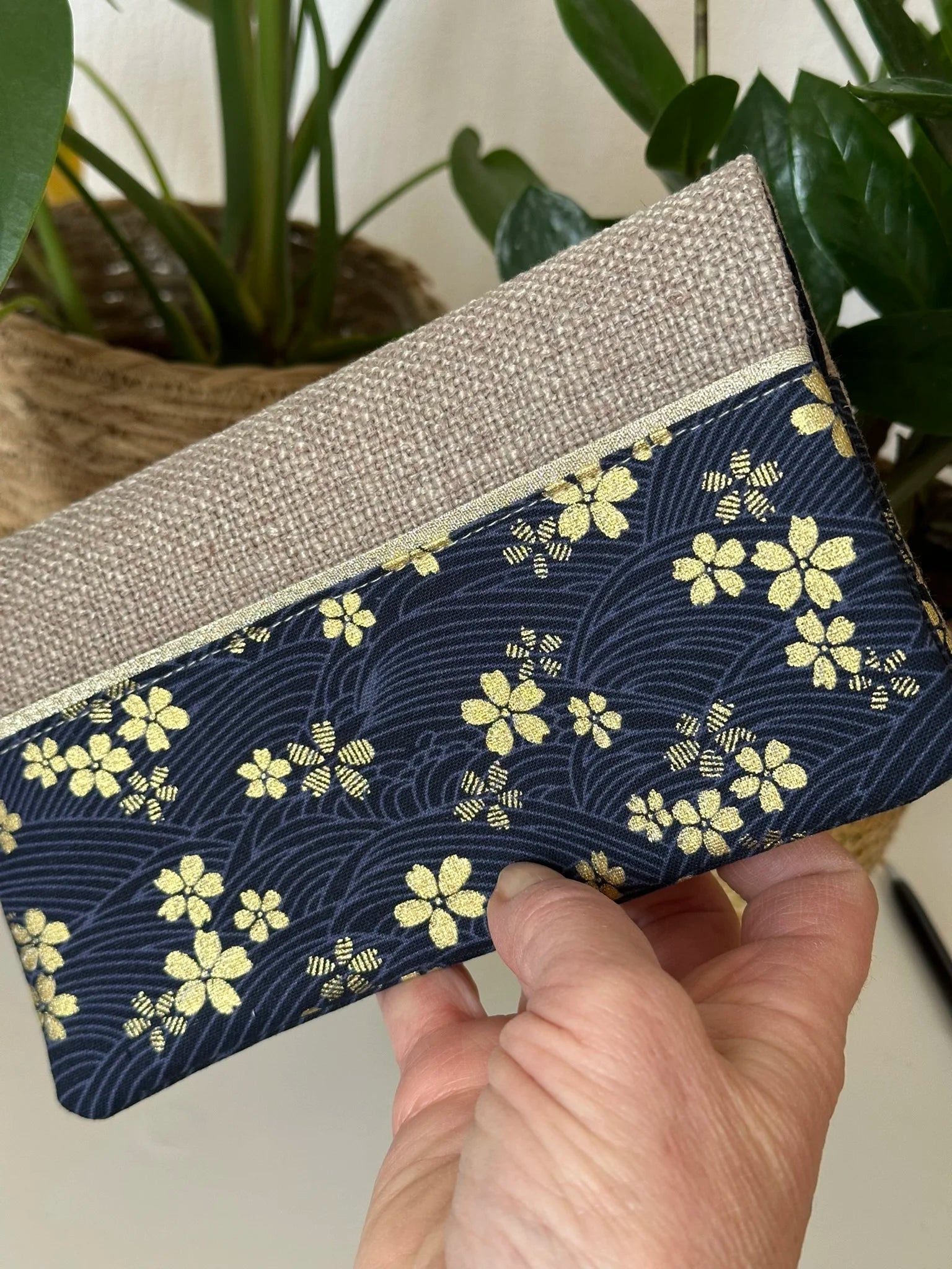 Le porte chéquier en lin et tissu japonais Sakura bleu tenu en main.