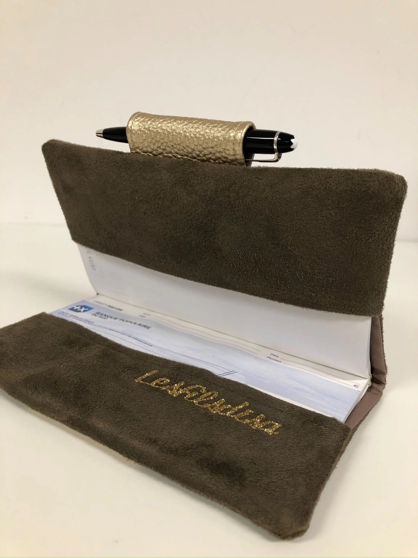 Le porte-chéquier marron et doré avec porte-stylo, ouvert.