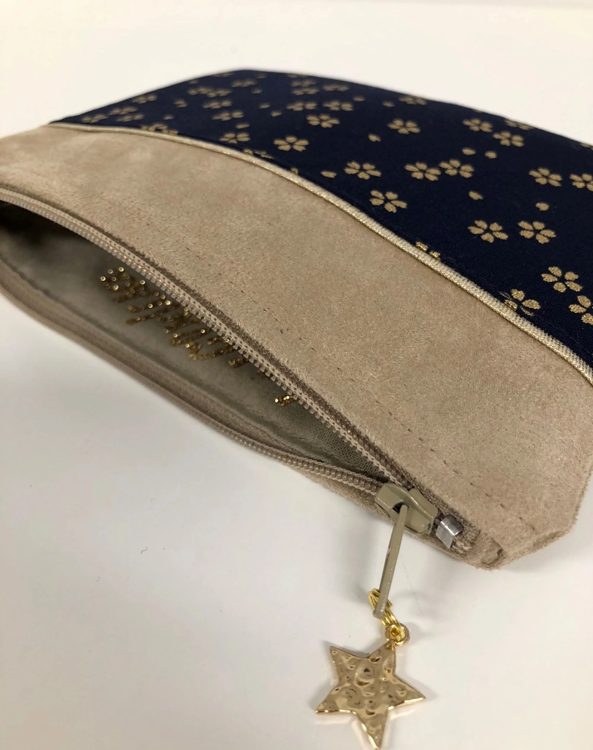 Le porte-monnaie beige et bleu nuit à fleurs dorées, ouvert.