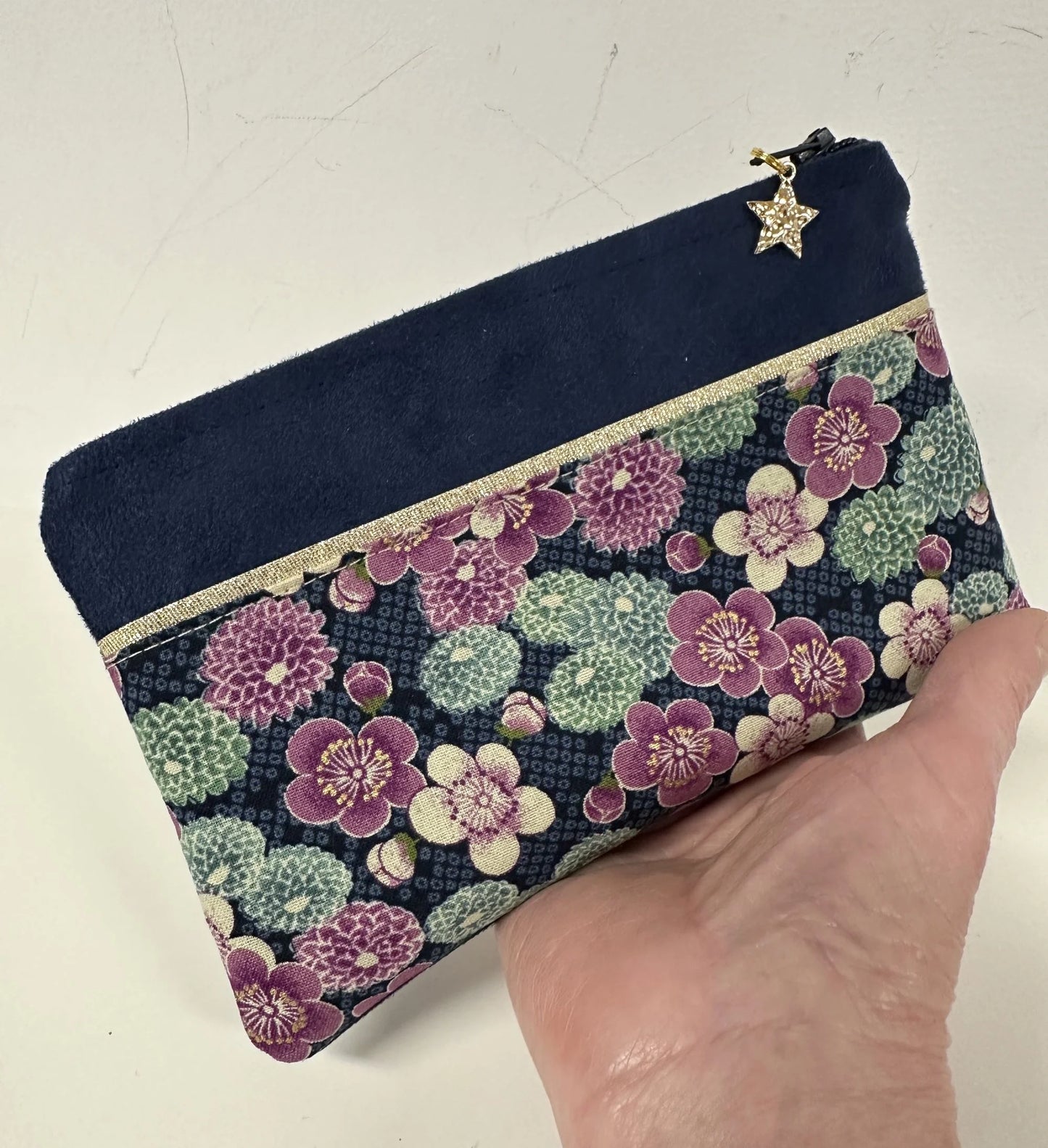 Le porte-monnaie bleu marine en tissu japonais à fleurs mauves, présenté en main.