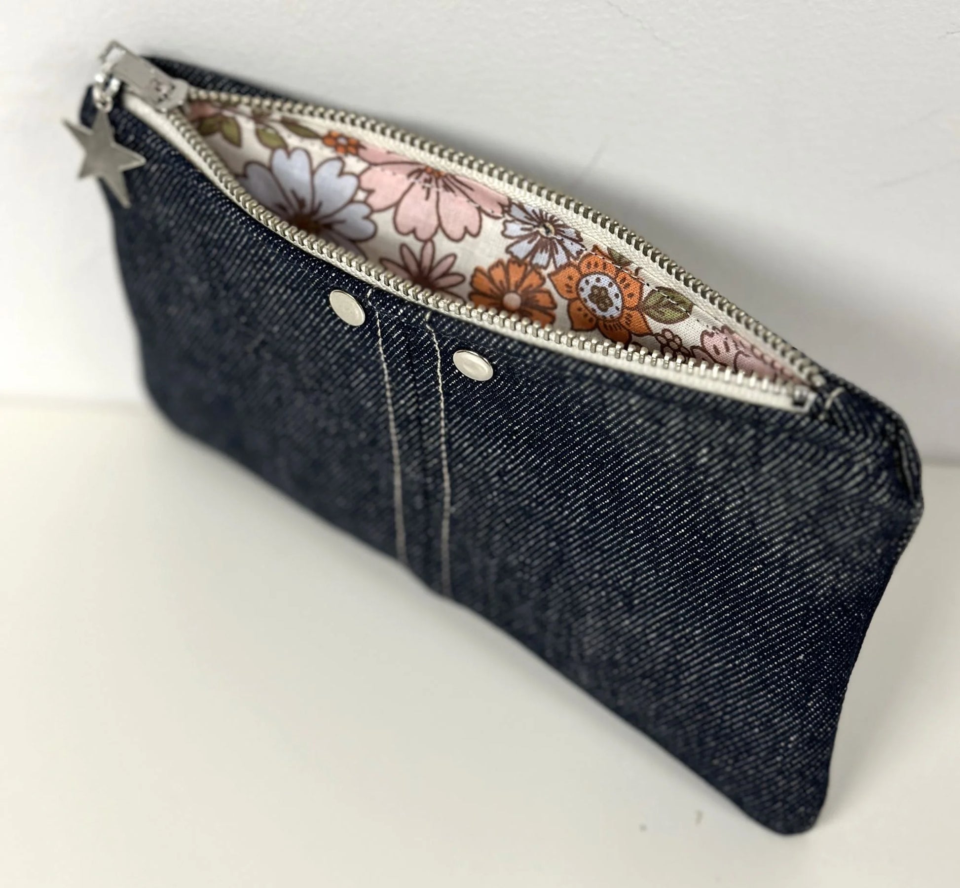 Le porte-monnaie en denim brut, sa doublure intérieure fleurie.