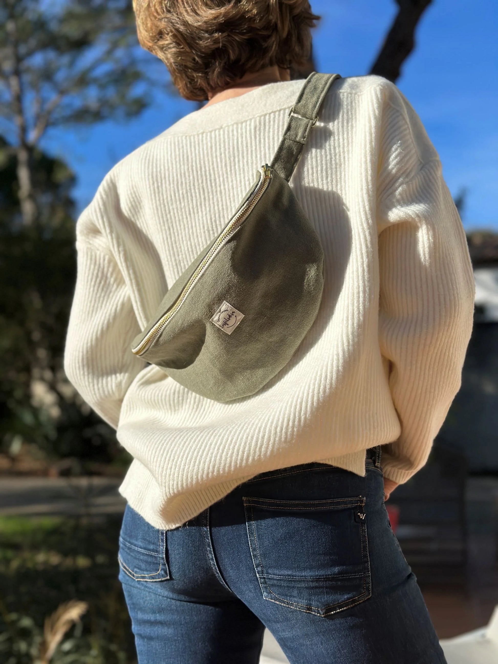 Le sac banane en toile vert kaki, porté en travers.