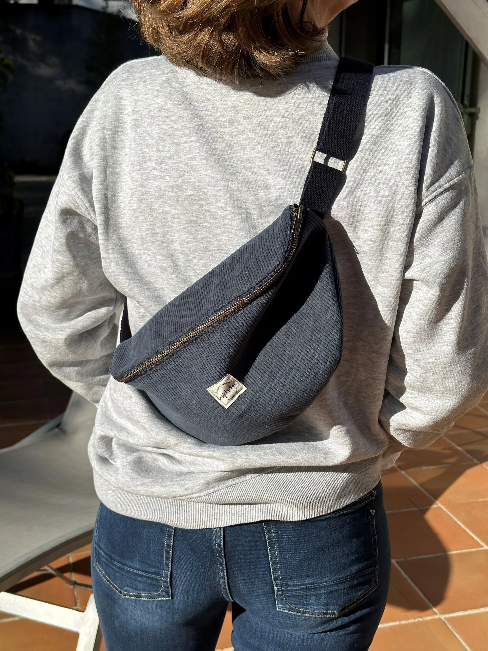 Le sac banane en velours côtelé bleu canard, porté en travers.