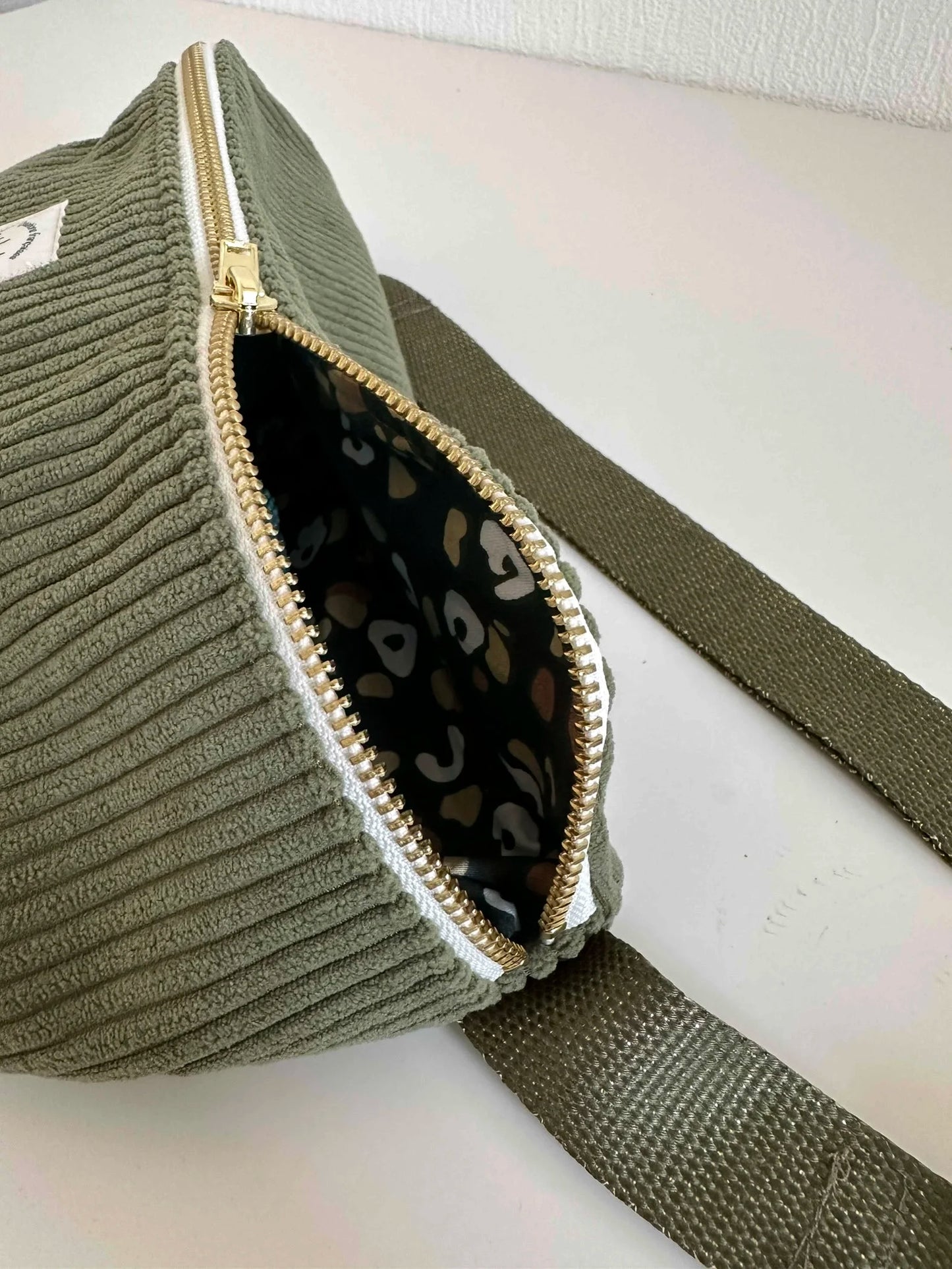 Le sac banane en velours cotelé vert armée, entrouvert.