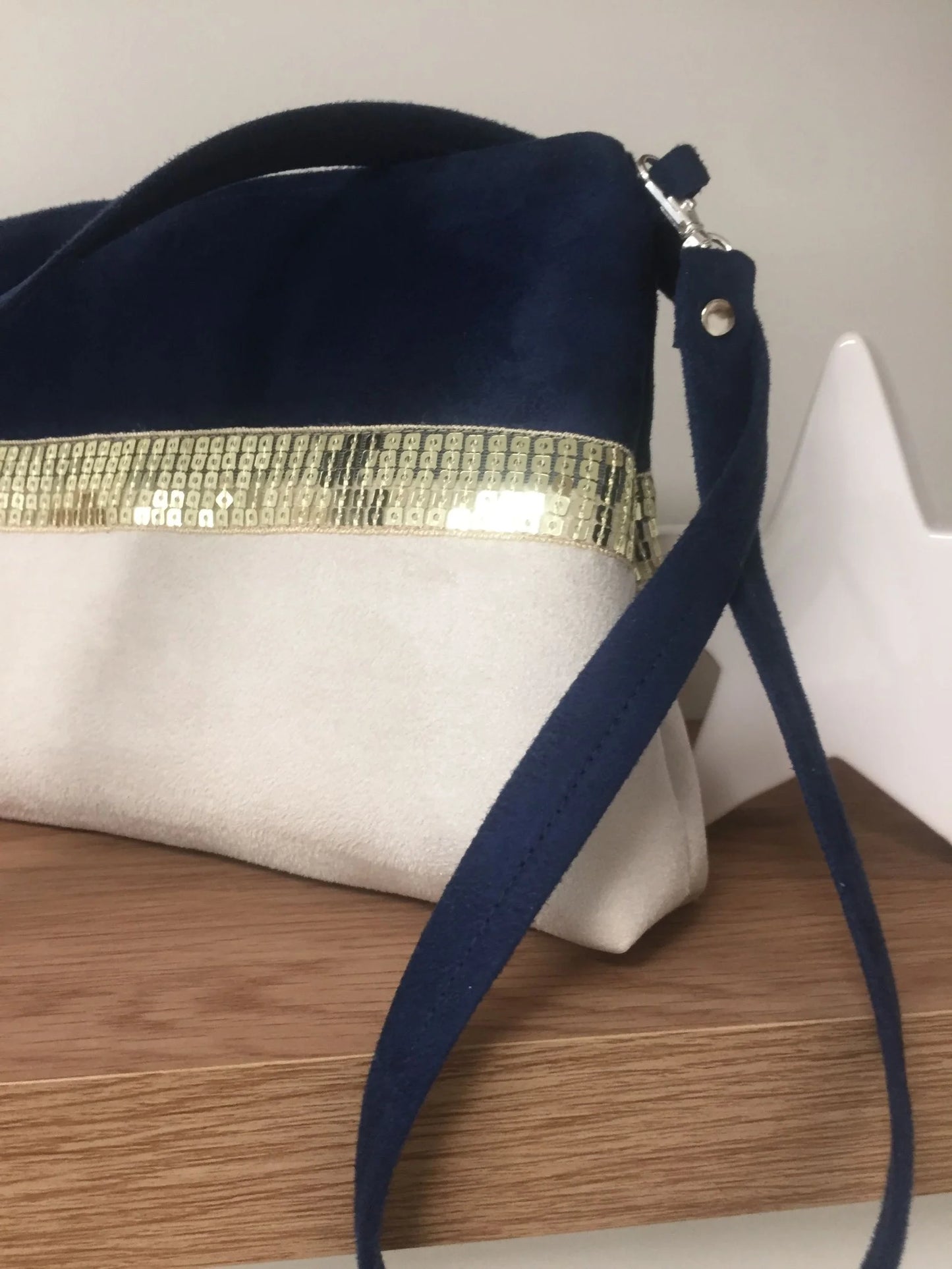 La bandoulière amovible du sac bandoulière Isa bleu marine et ivoire à paillettes dorées.