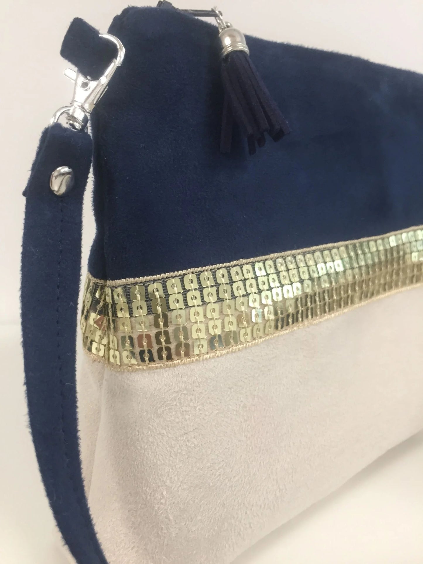 Vue latérale du sac bandoulière Isa bleu marine et ivoire à paillettes dorées.