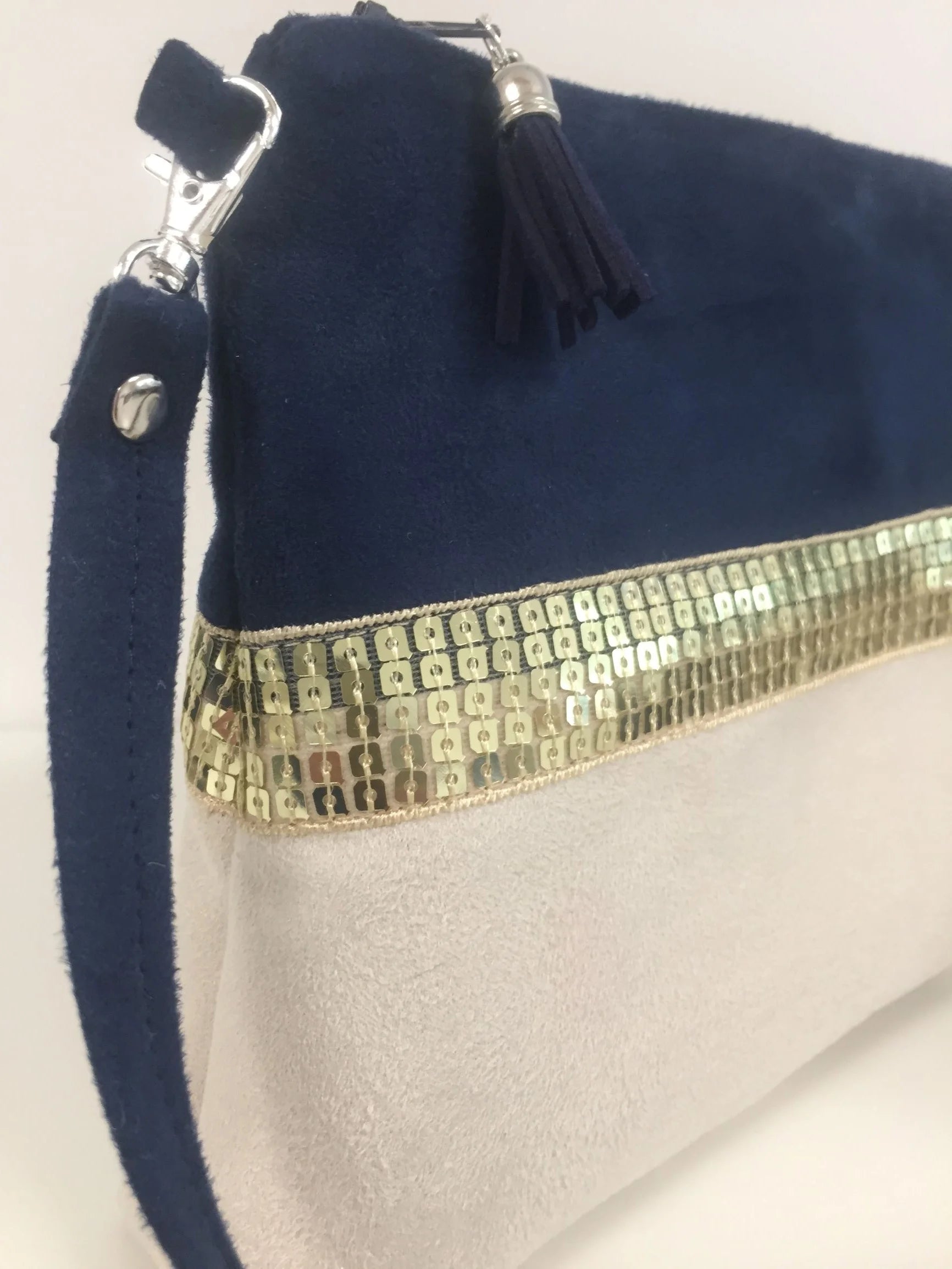 Vue latérale du sac bandoulière Isa bleu marine et ivoire à paillettes dorées.
