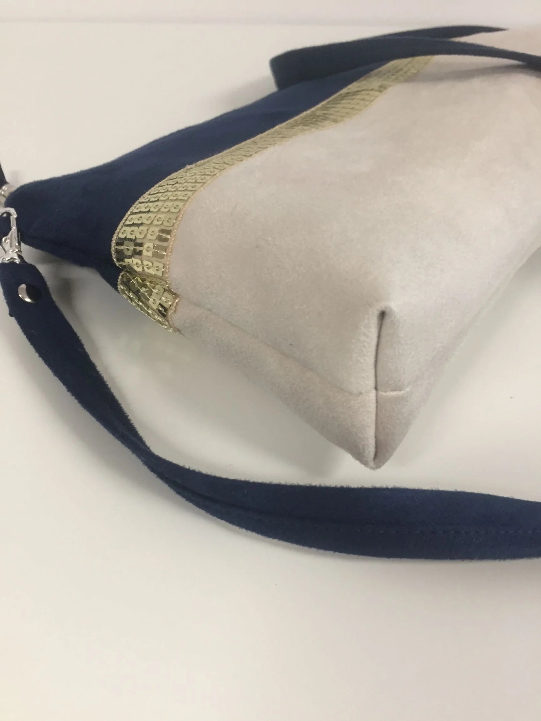 Le fond du sac bandoulière Isa bleu marine et ivoire à paillettes dorées.