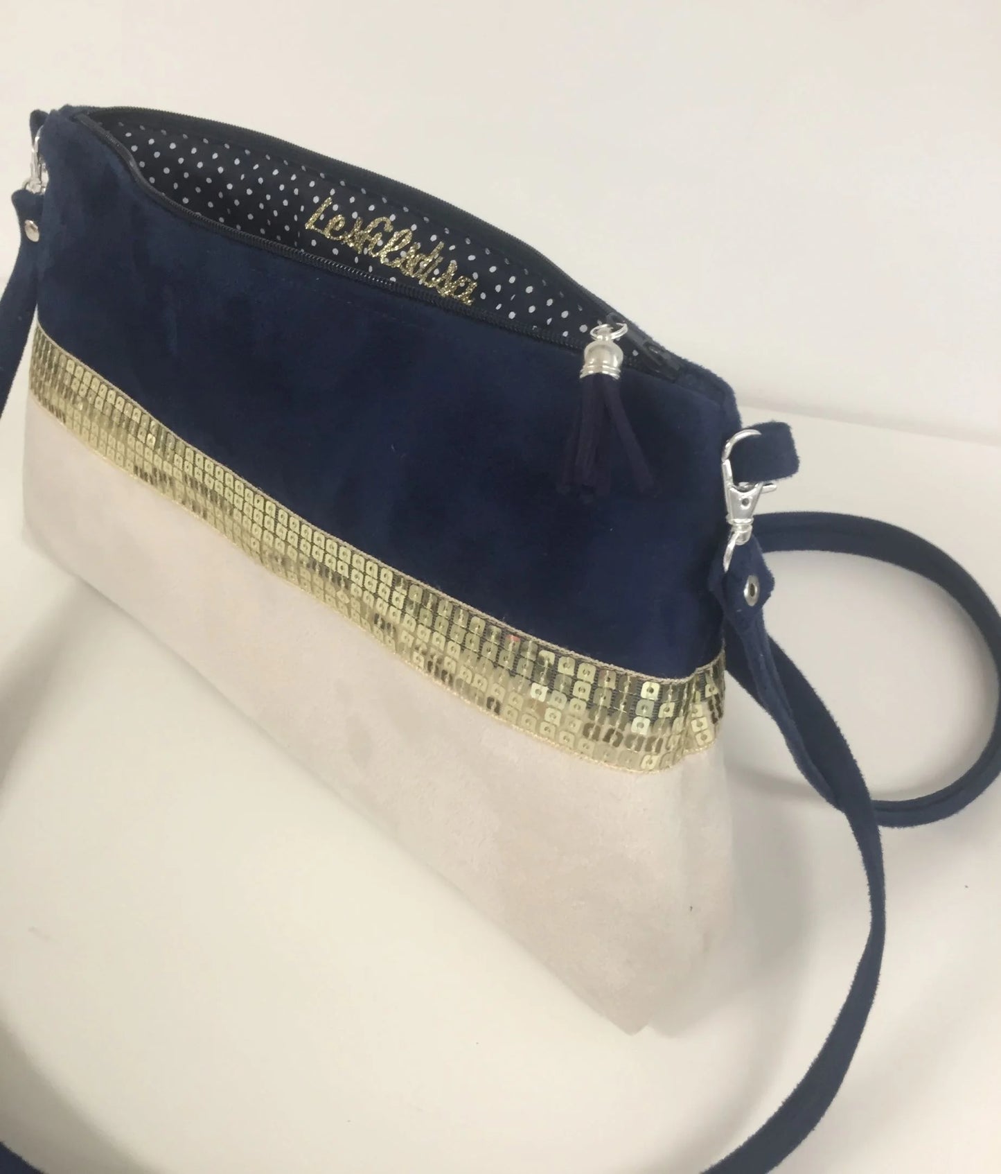 Le sac bandoulière Isa bleu marine et ivoire à paillettes dorées, ouvert.
