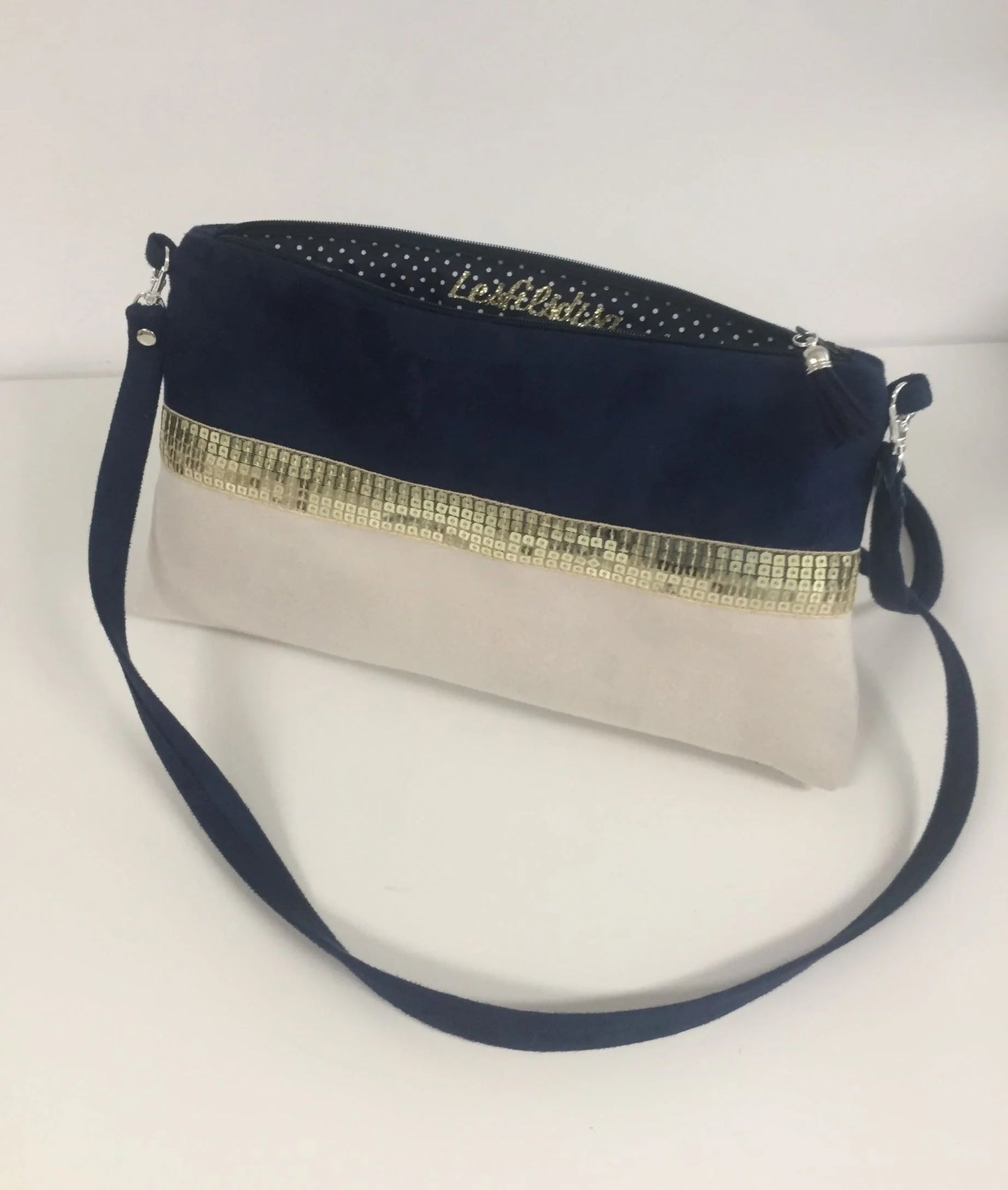 La doublure intérieure du sac bandoulière Isa bleu marine et ivoire à paillettes dorées.