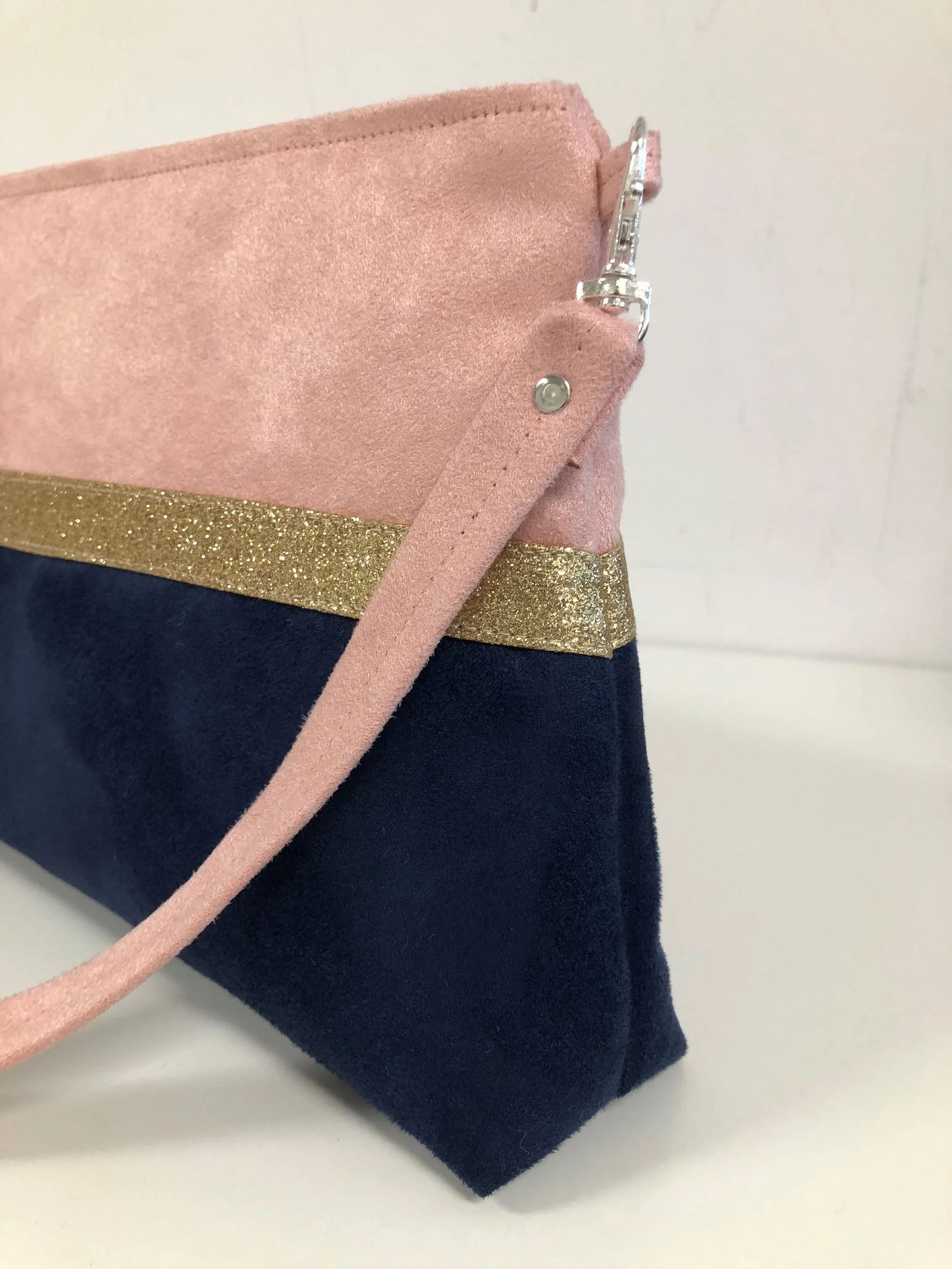 La bandoulière amovible du sac bandoulière Isa rose poudré et bleu marine à paillettes dorées.