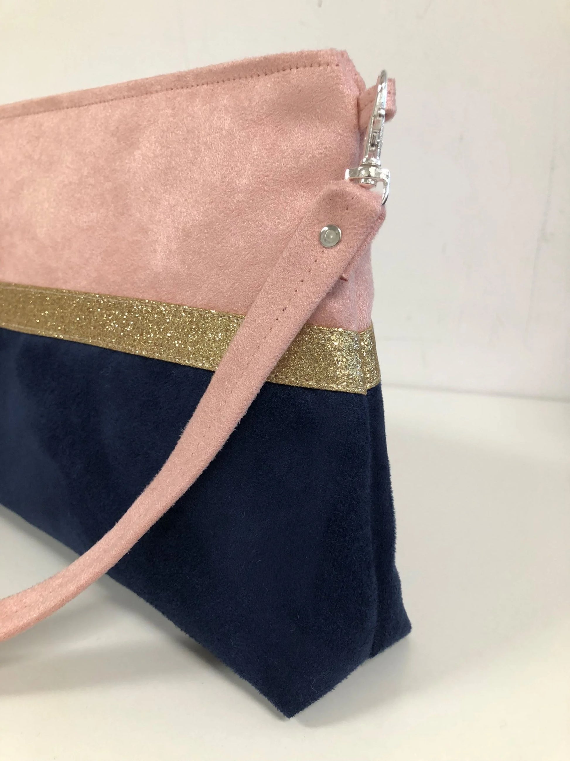 La bandoulière amovible du sac bandoulière Isa rose poudré et bleu marine à paillettes dorées.