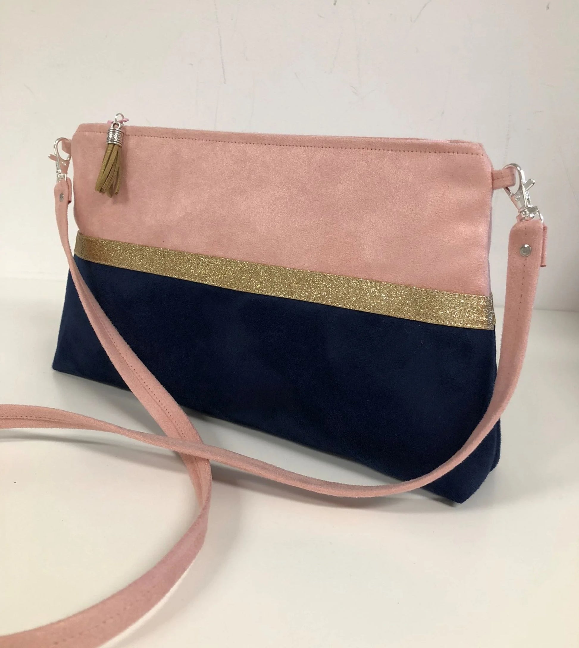 Le sac bandoulière Isa rose poudré et bleu marine à paillettes dorées.