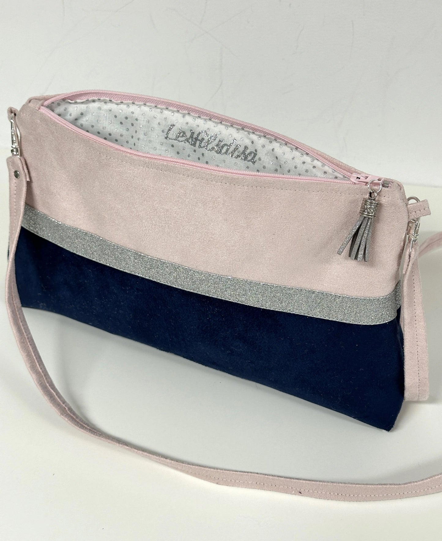 La doublure intérieure du sac bandoulière rose pâle et bleu marine à paillettes argentées.