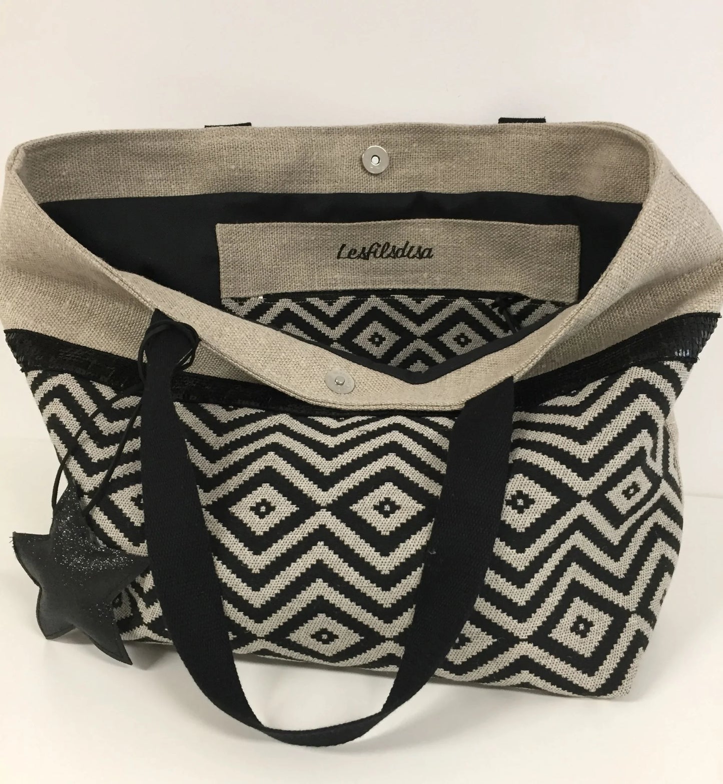 La poche zippée intérieure du sac cabas Isa en lin et chevrons noirs à paillettes.