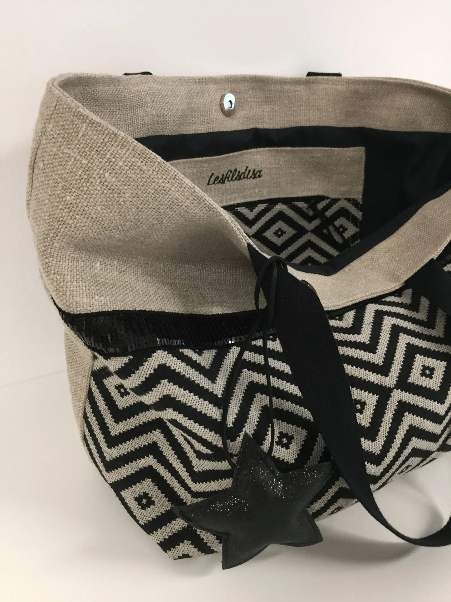 Le sac cabas Isa en lin et chevrons noirs à paillettes avec fermoir magnétique, ouvert.