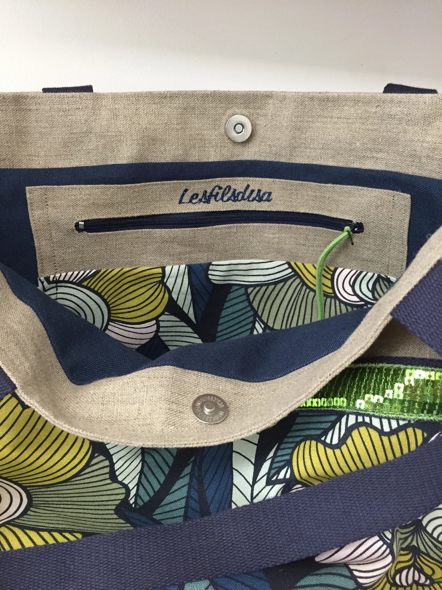 La poche zippée intérieure du sac cabas Isa en lin et fleurs Arty et paillettes vertes.