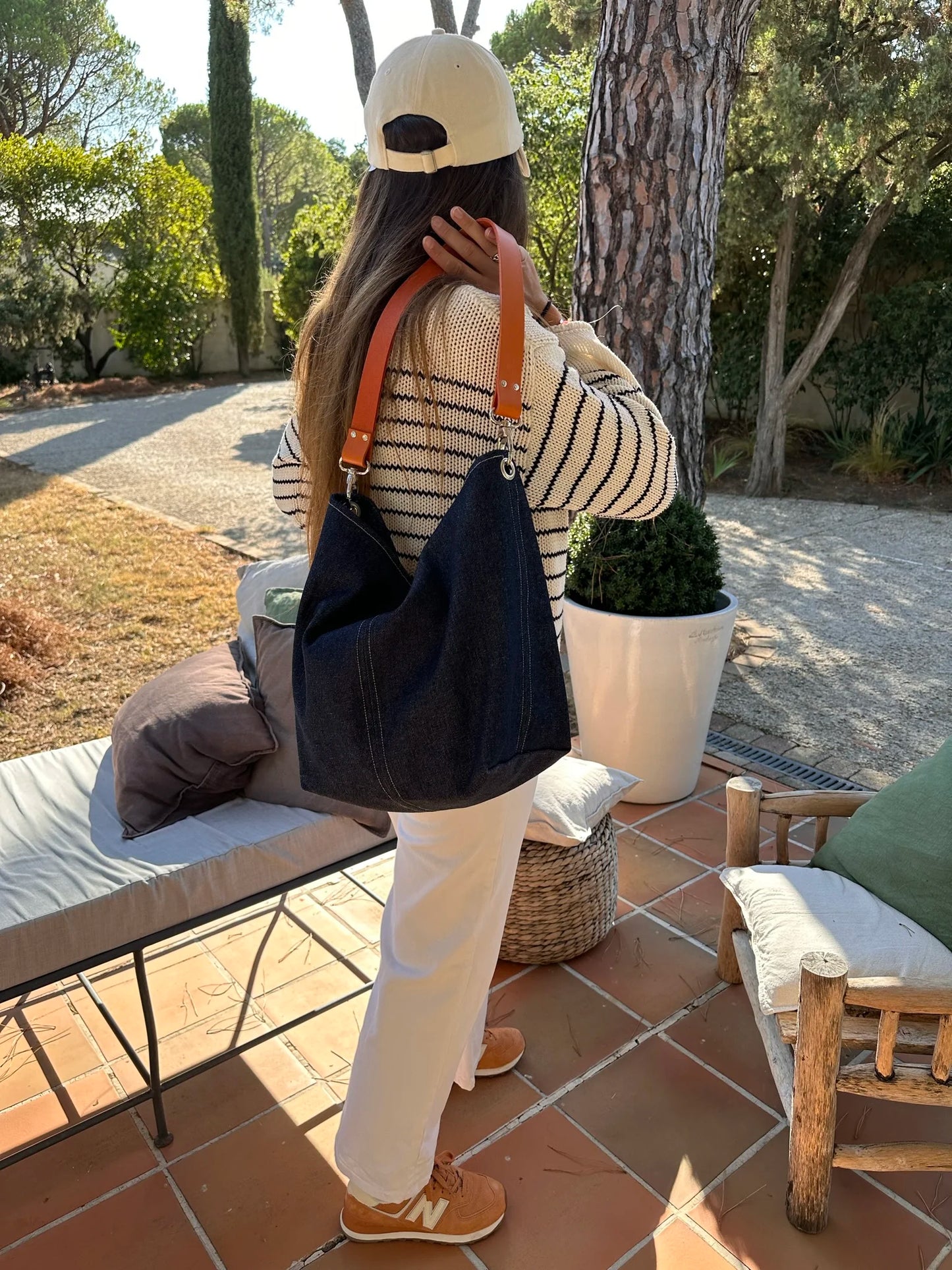 Jeune femme portant le sac hobo en denim et son anse en cuir orange .