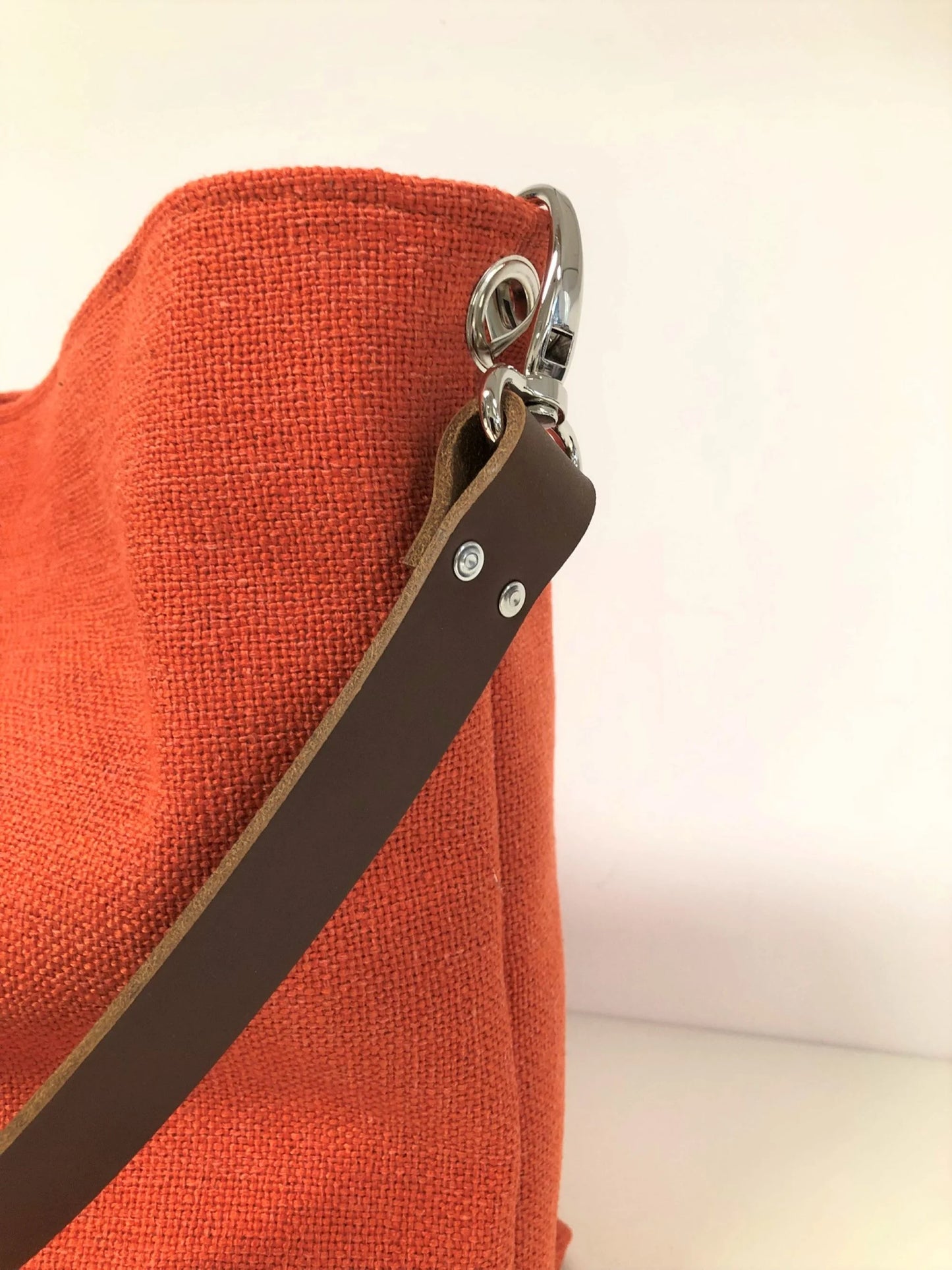 Vue de détail de l'anse en cuir marron du sac Hobo Lesfilsdisa en lin orange