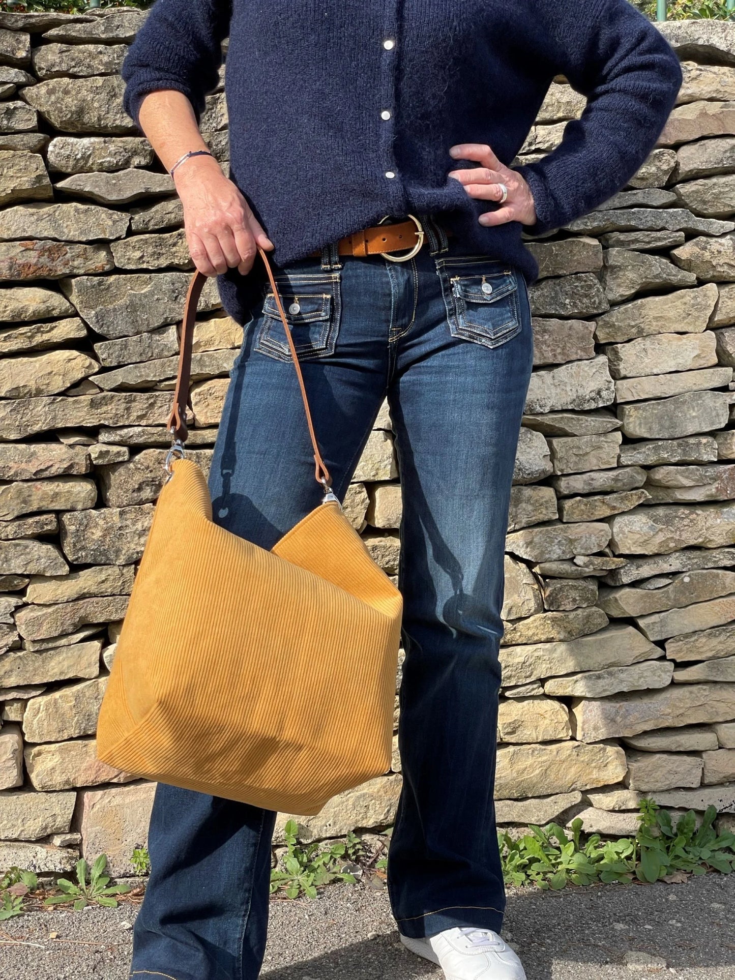 Le sac Hobo Lesfilsdisa en velours côtelé jaune moutarde et son anse en cuir marron amovible porté à la main