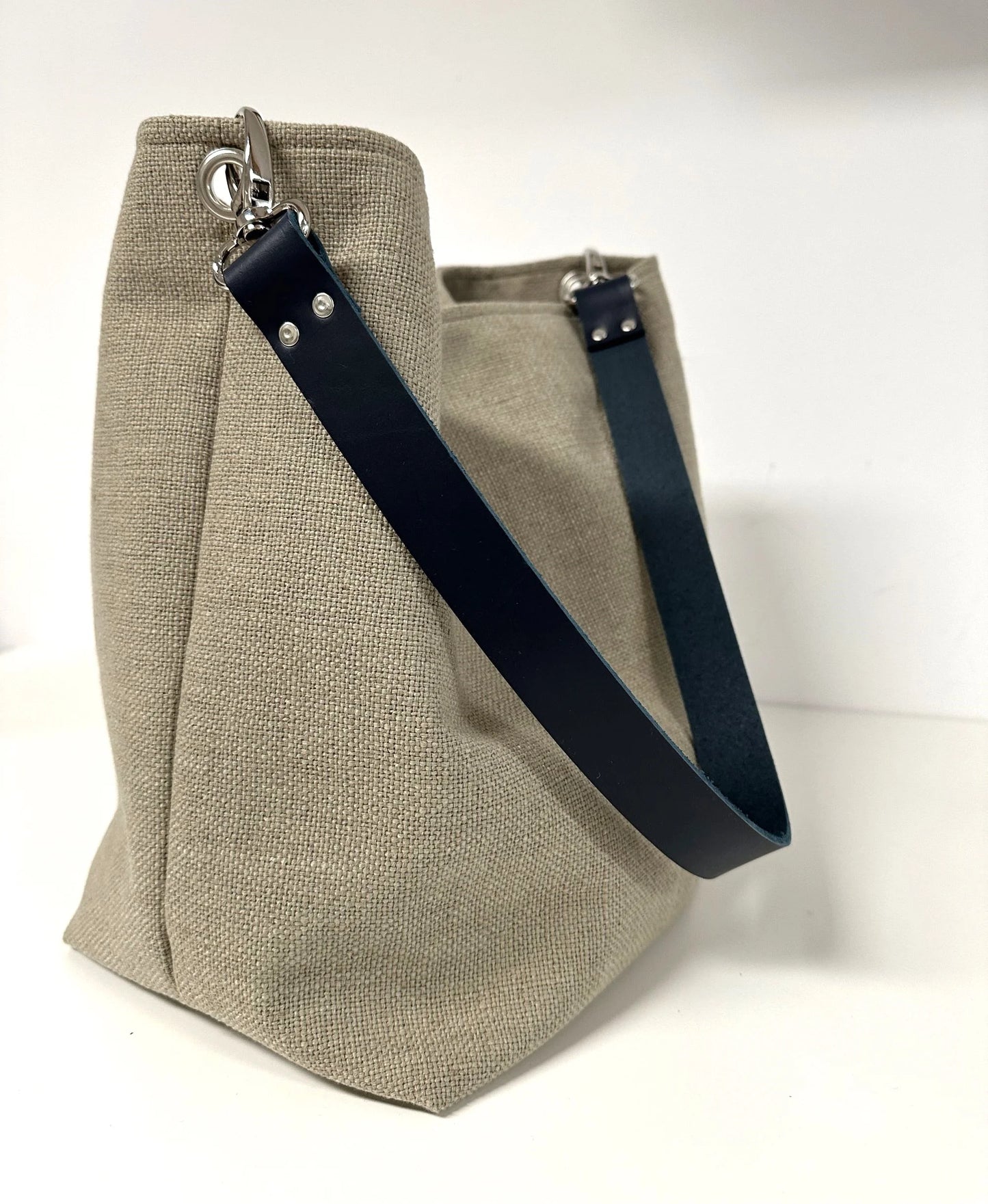 Le sac Hobo en lin beige et son anse en cuir bleu marine amovible