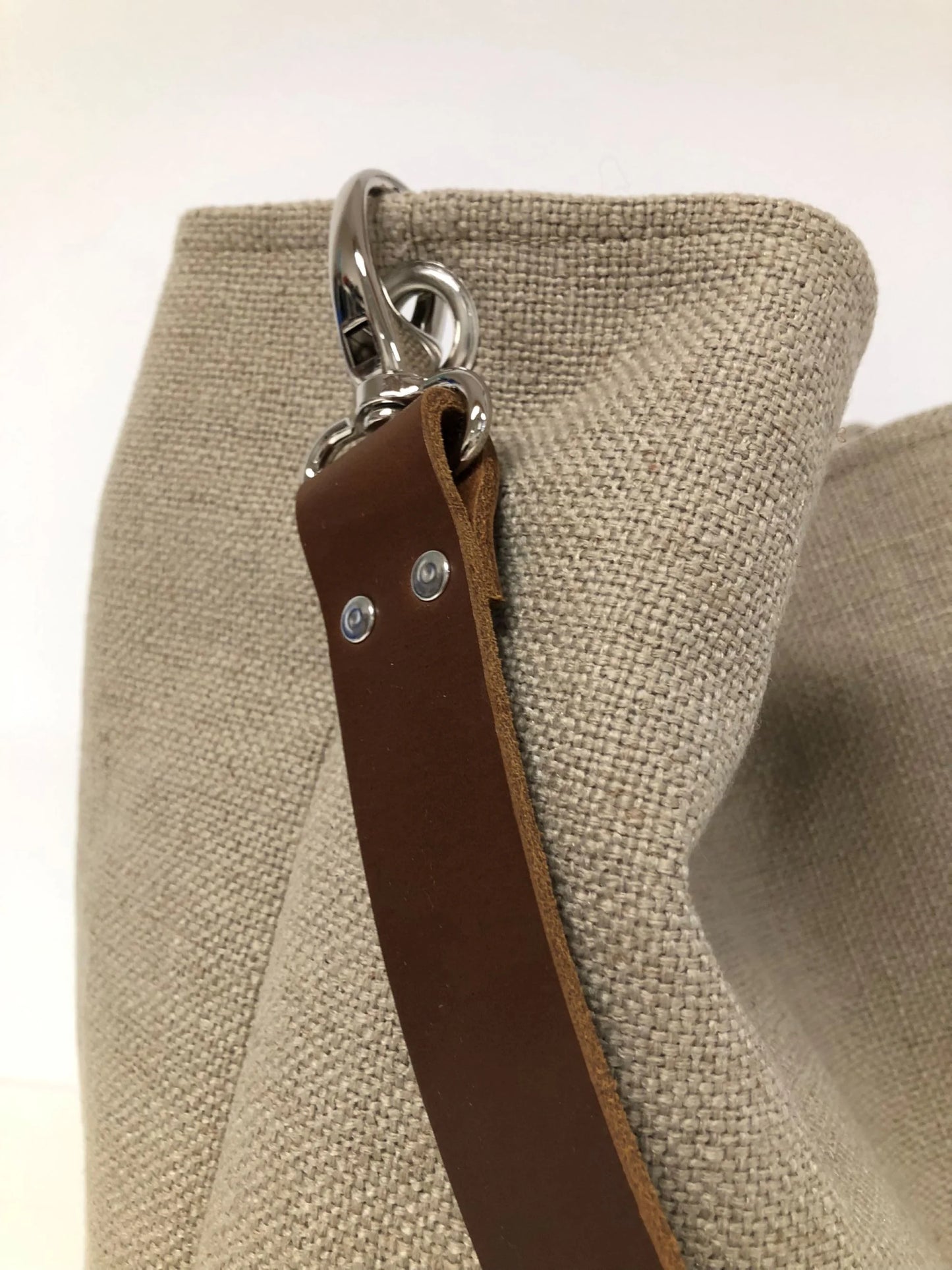 Vue détaillée de l'anse en cuir marron du sac hobo en lin beige.