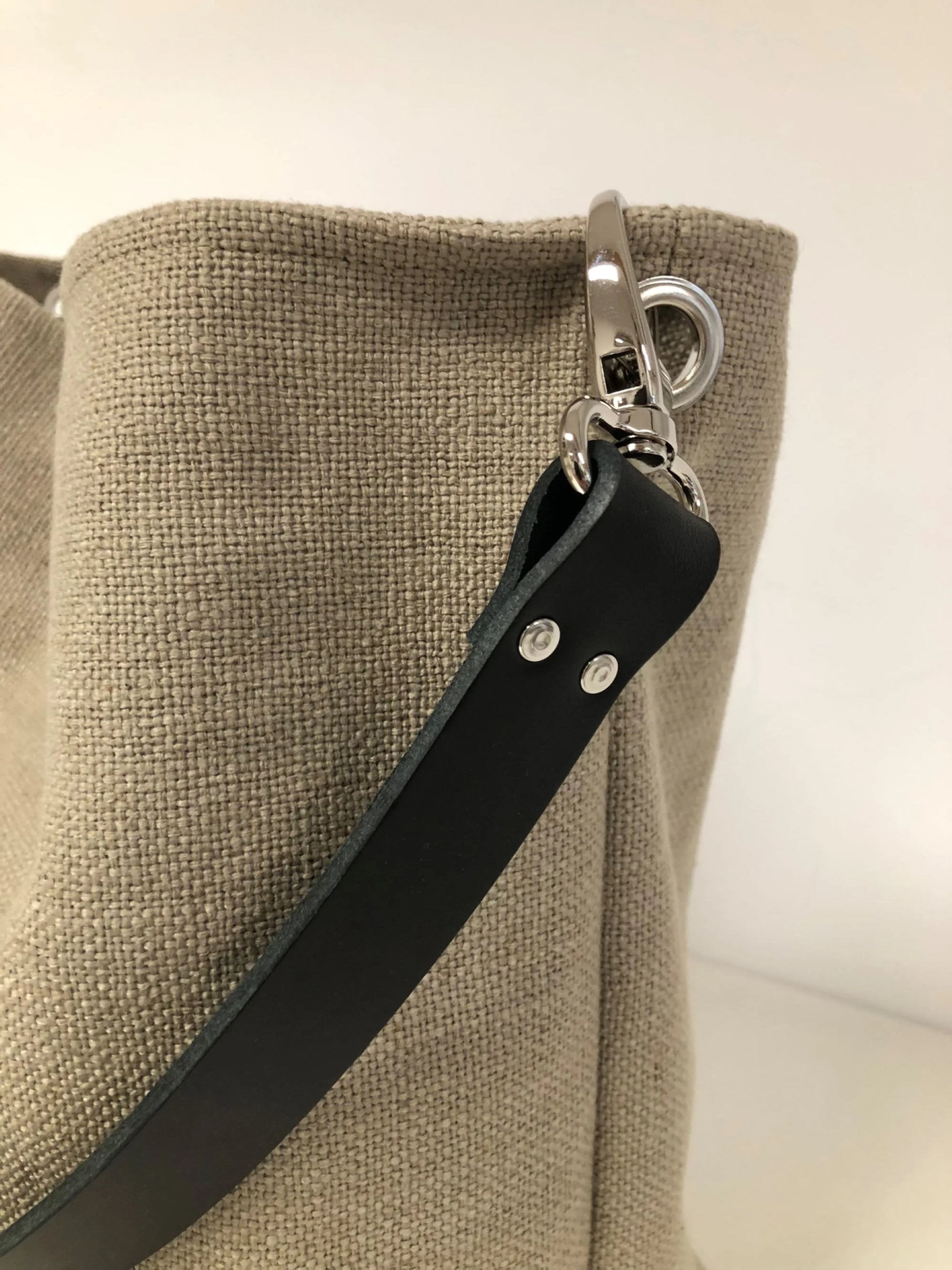 L'anse en cuir noir amovible du sac hobo en lin beige.