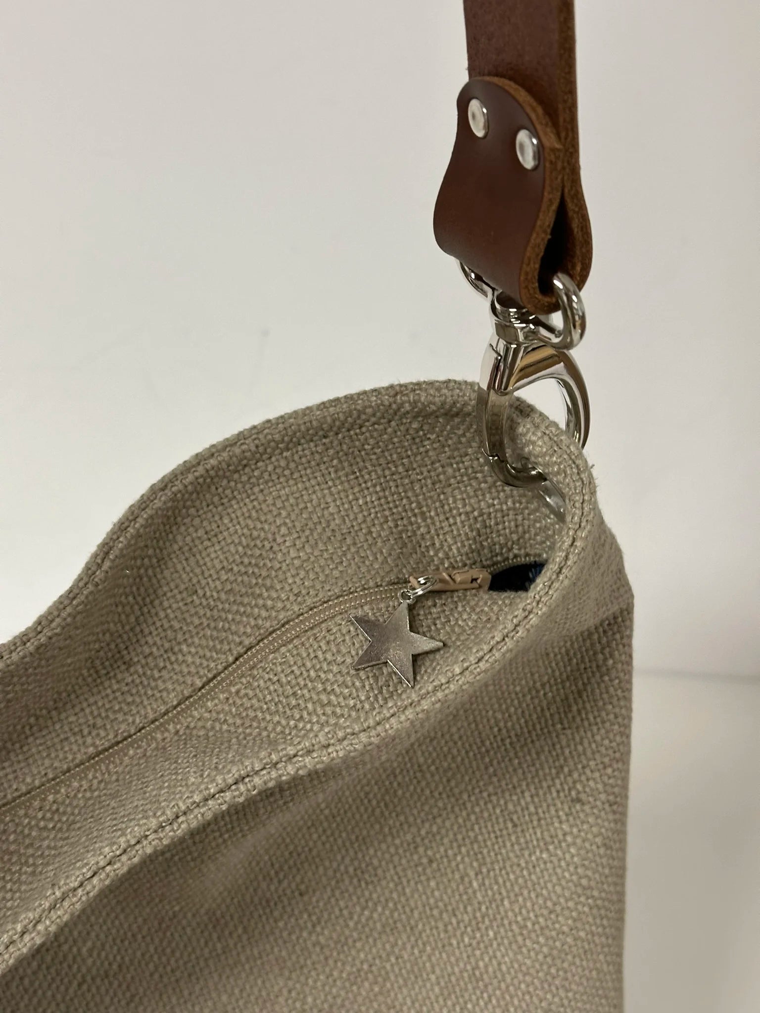 Le sac hobo en lin beige avec la fermeture éclair.