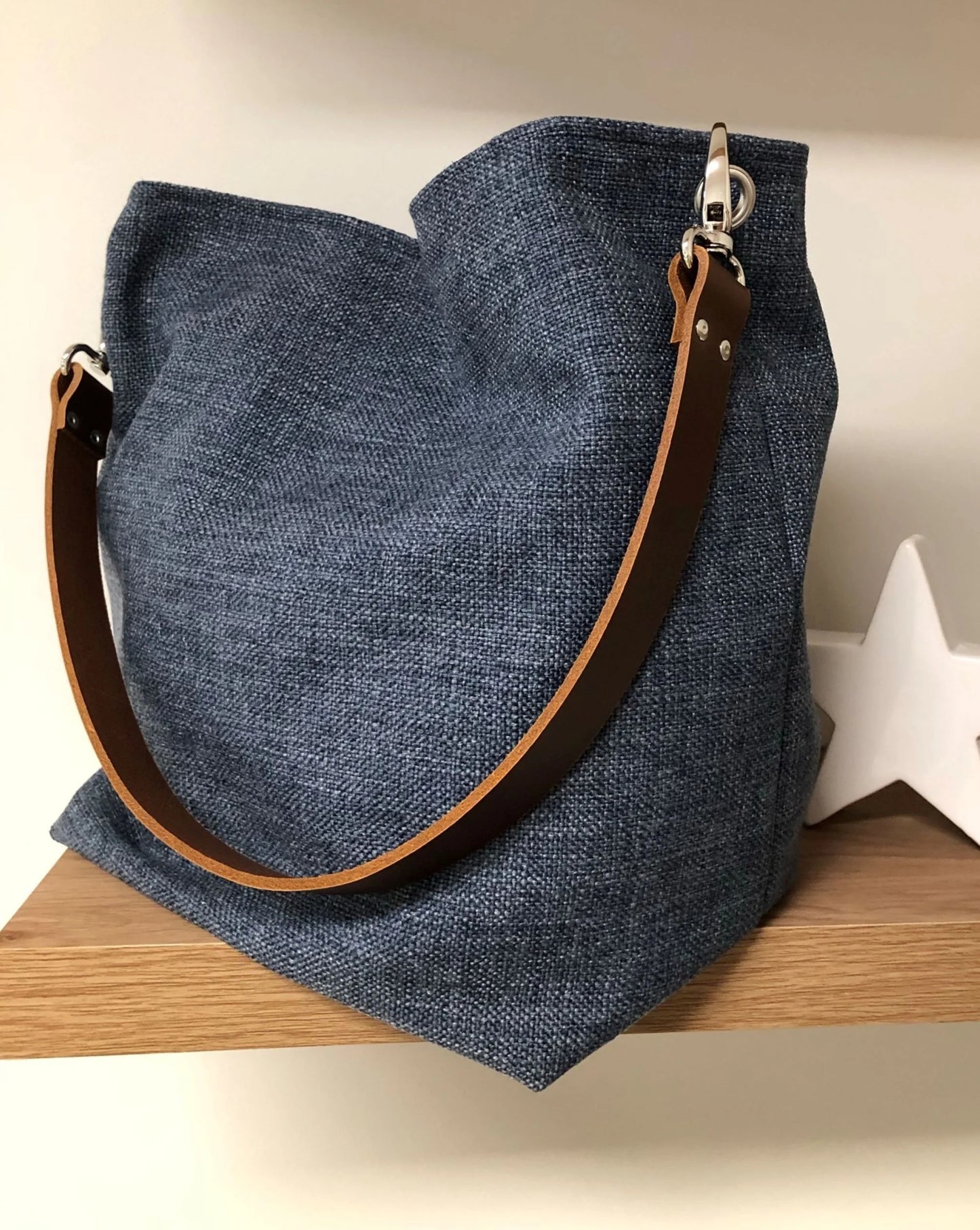 Le sac Hobo en lin bleu et son anse en cuir marron.