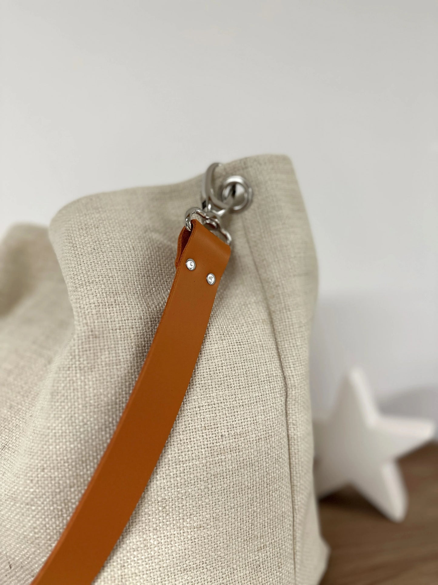 Vue détaillée de l'anse en cuir orange du sac hobo en lin ivoire.