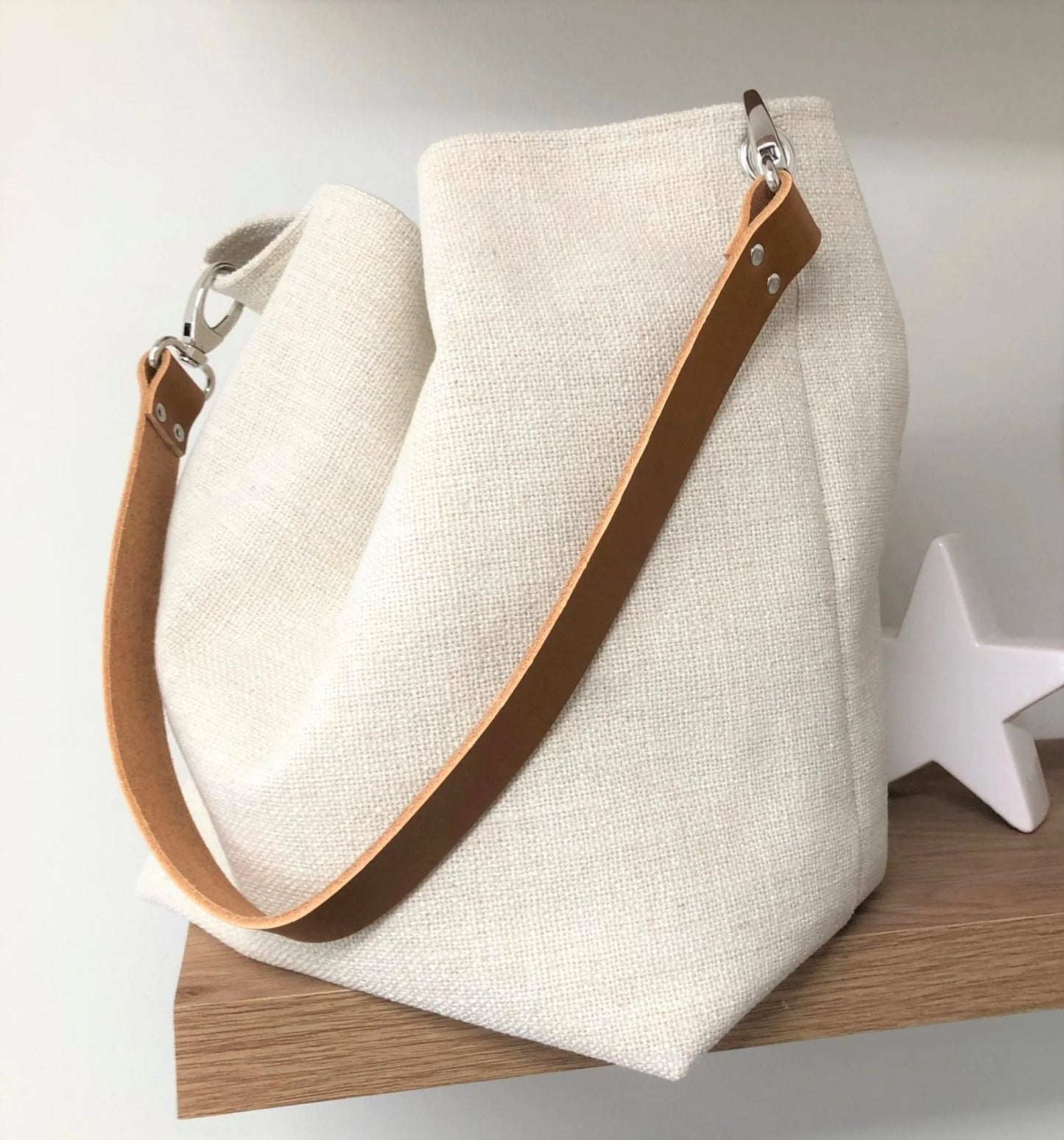 Le sac Hobo en lin ivoire et son anse en cuir fauve.