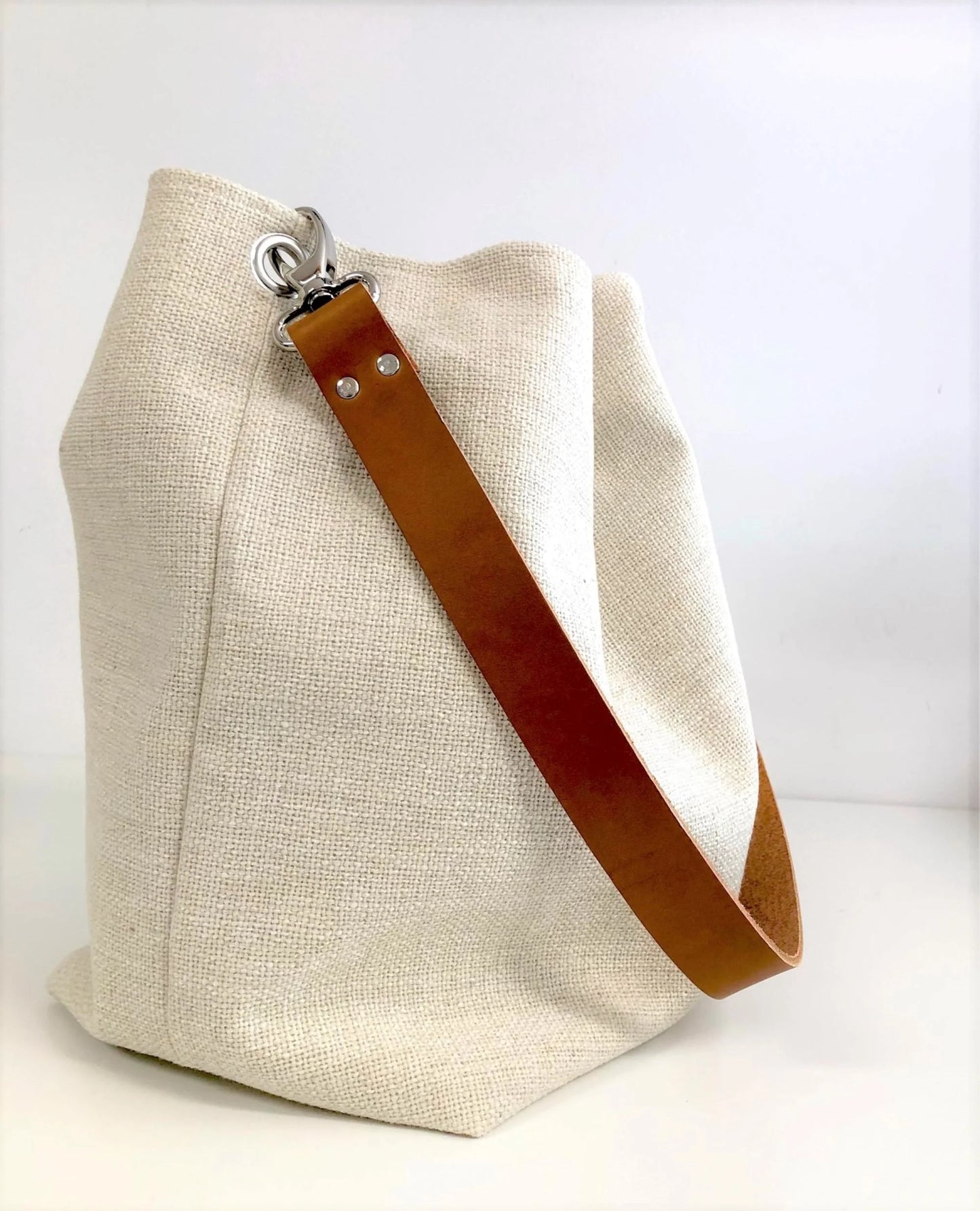 Vue latérale du sac Hobo en lin ivoire et anse en cuir fauve.