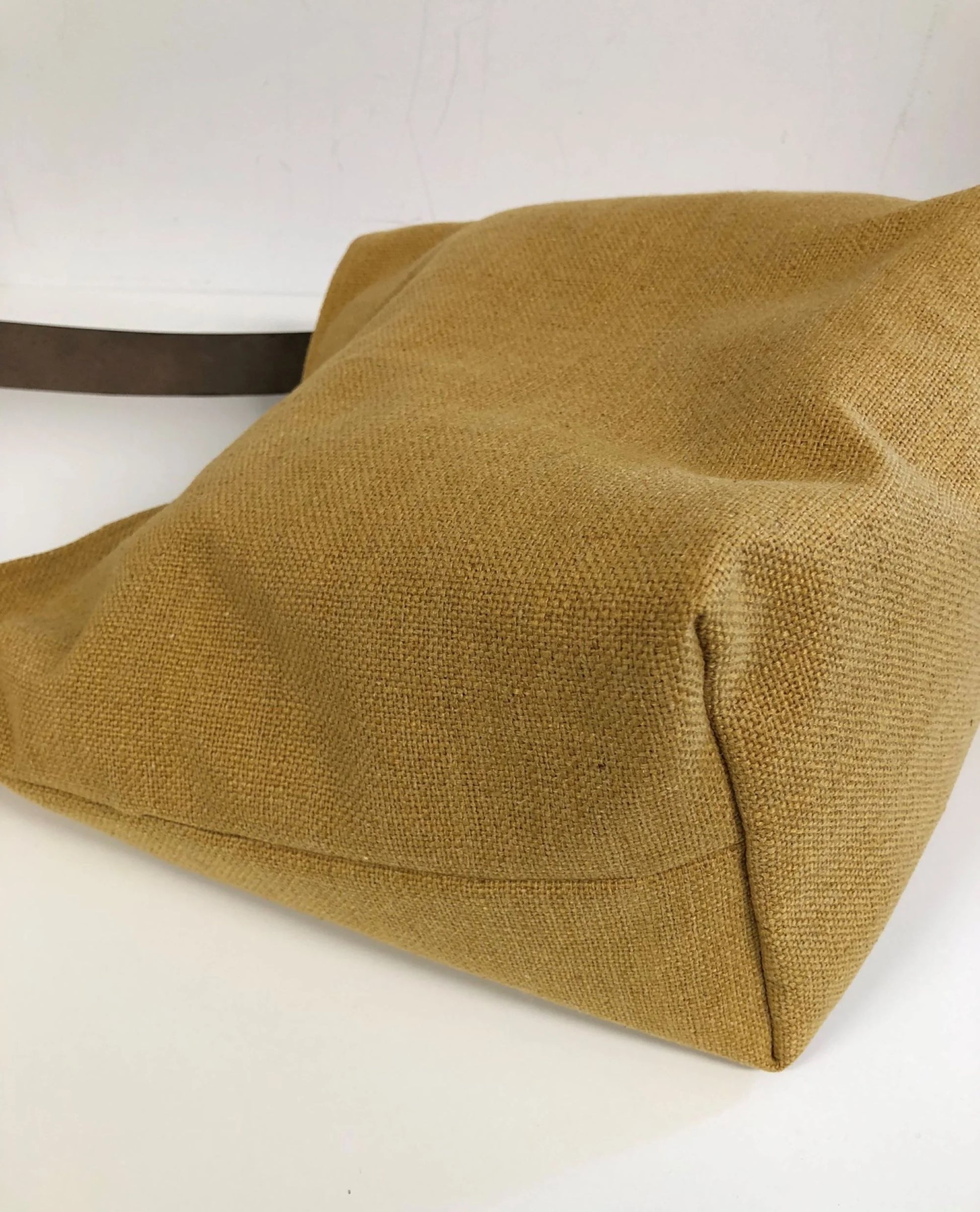 Le fond du sac hobo en lin jaune moutarde et son anse en cuir marron amovible.