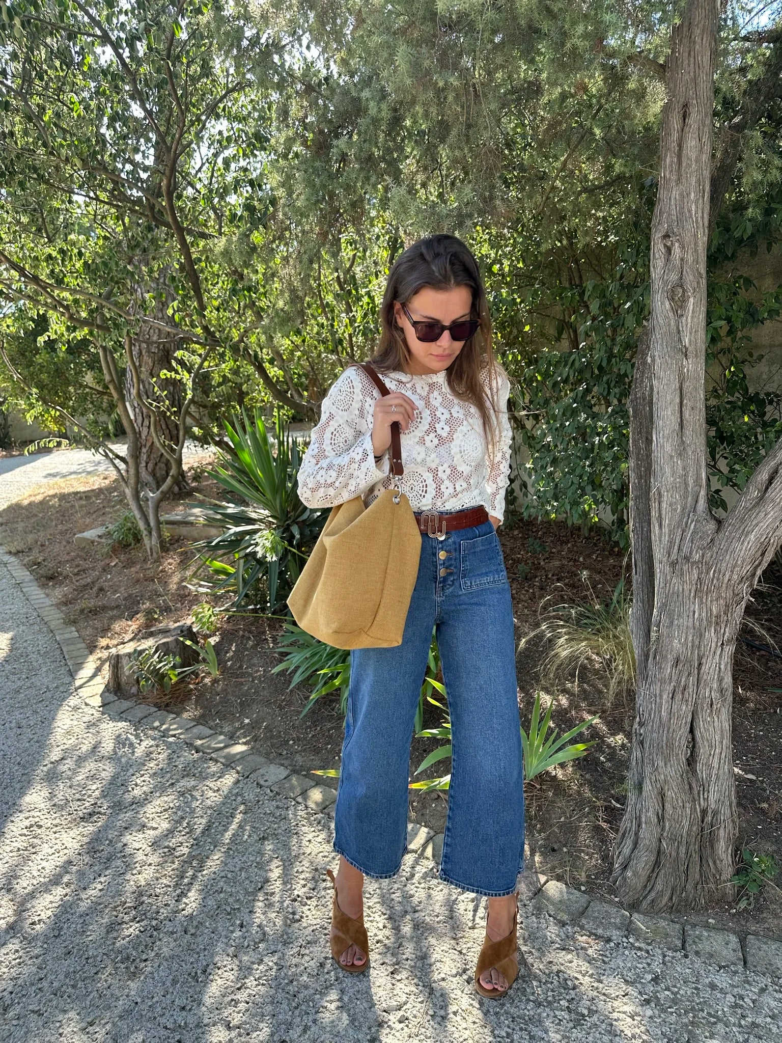 Femme portant à l'épaule le sac hobo en lin jaune moutarde et son anse en cuir marron amovible.