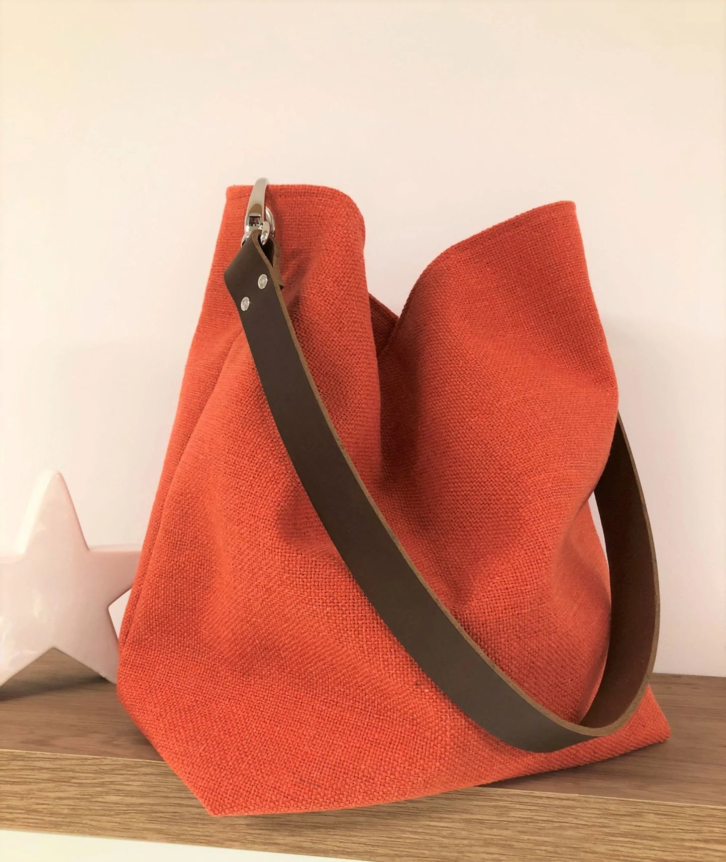 Le sac Hobo en lin orangé et son anse en cuir marron amovible.