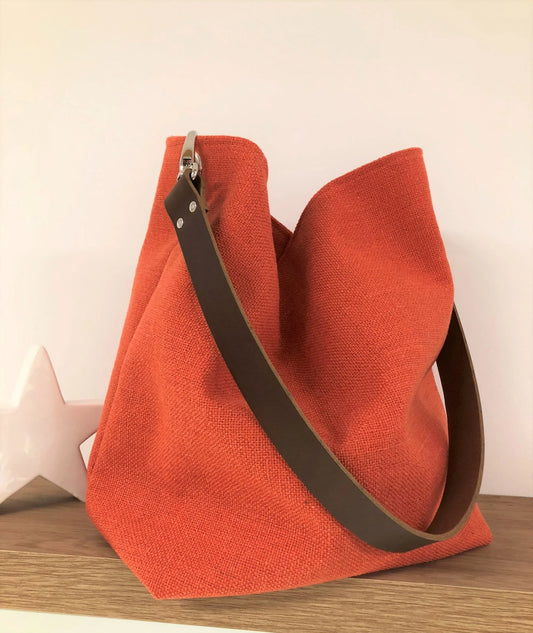 Le sac Hobo en lin orangé et son anse en cuir marron amovible.