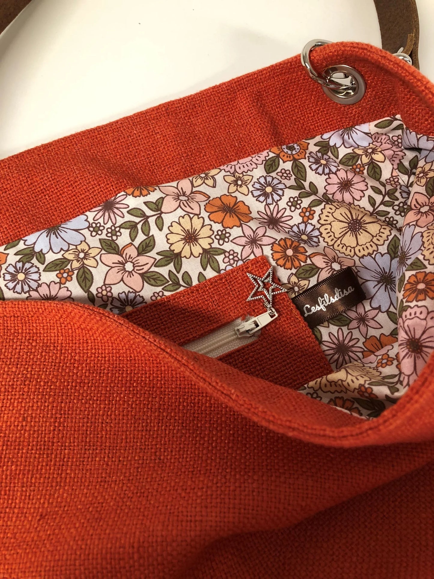 La poche intérieure zippée du sac Hobo en lin orange et son anse en cuir marron.