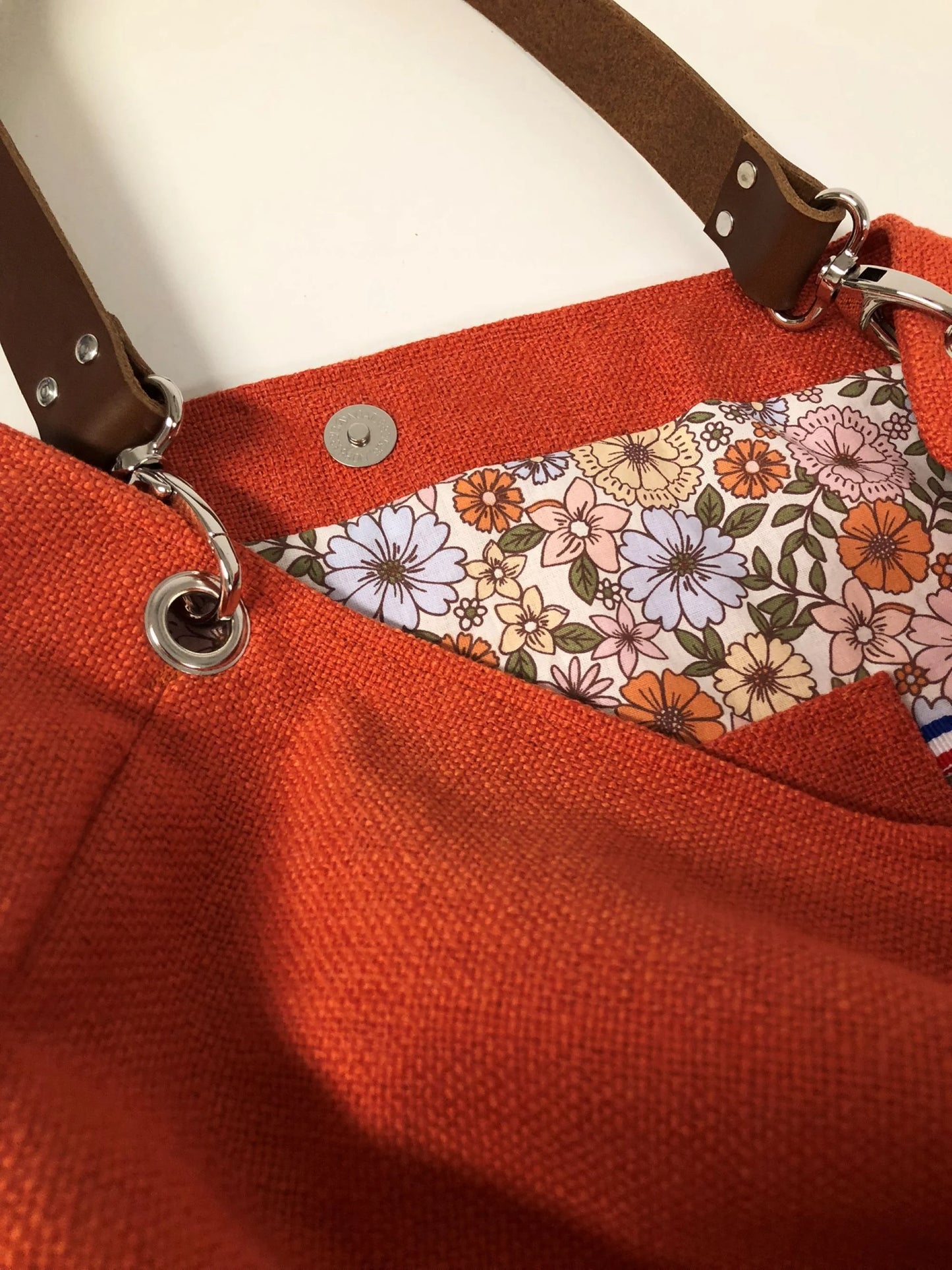 La poche plaquée intérieure du sac Hobo en lin orange et son anse en cuir marron.