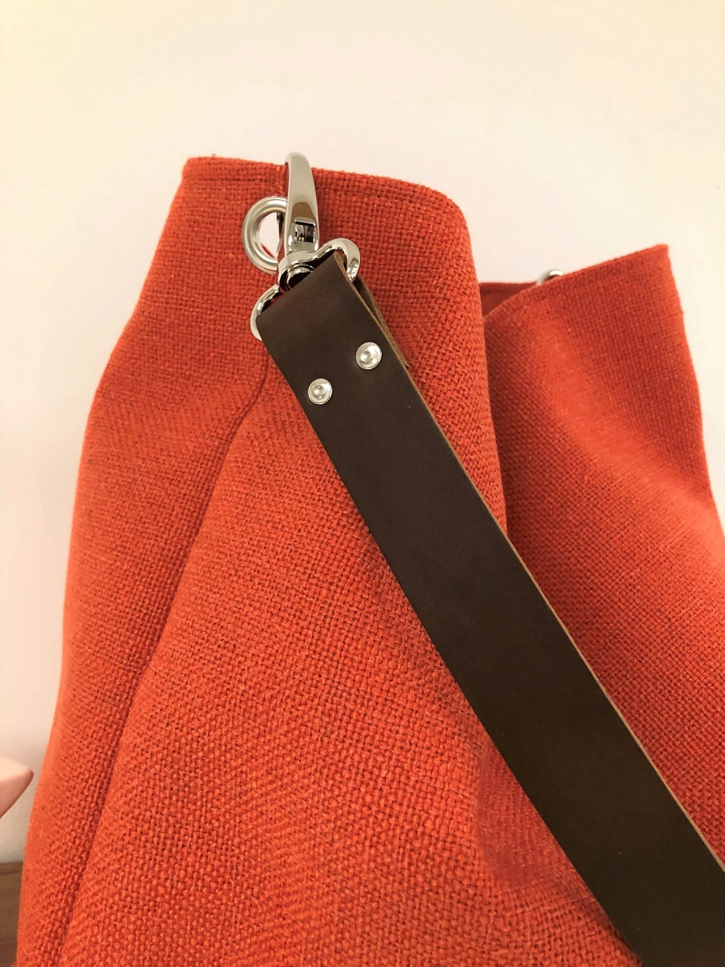 L'anse en cuir amovible du sac Hobo en lin orangé.