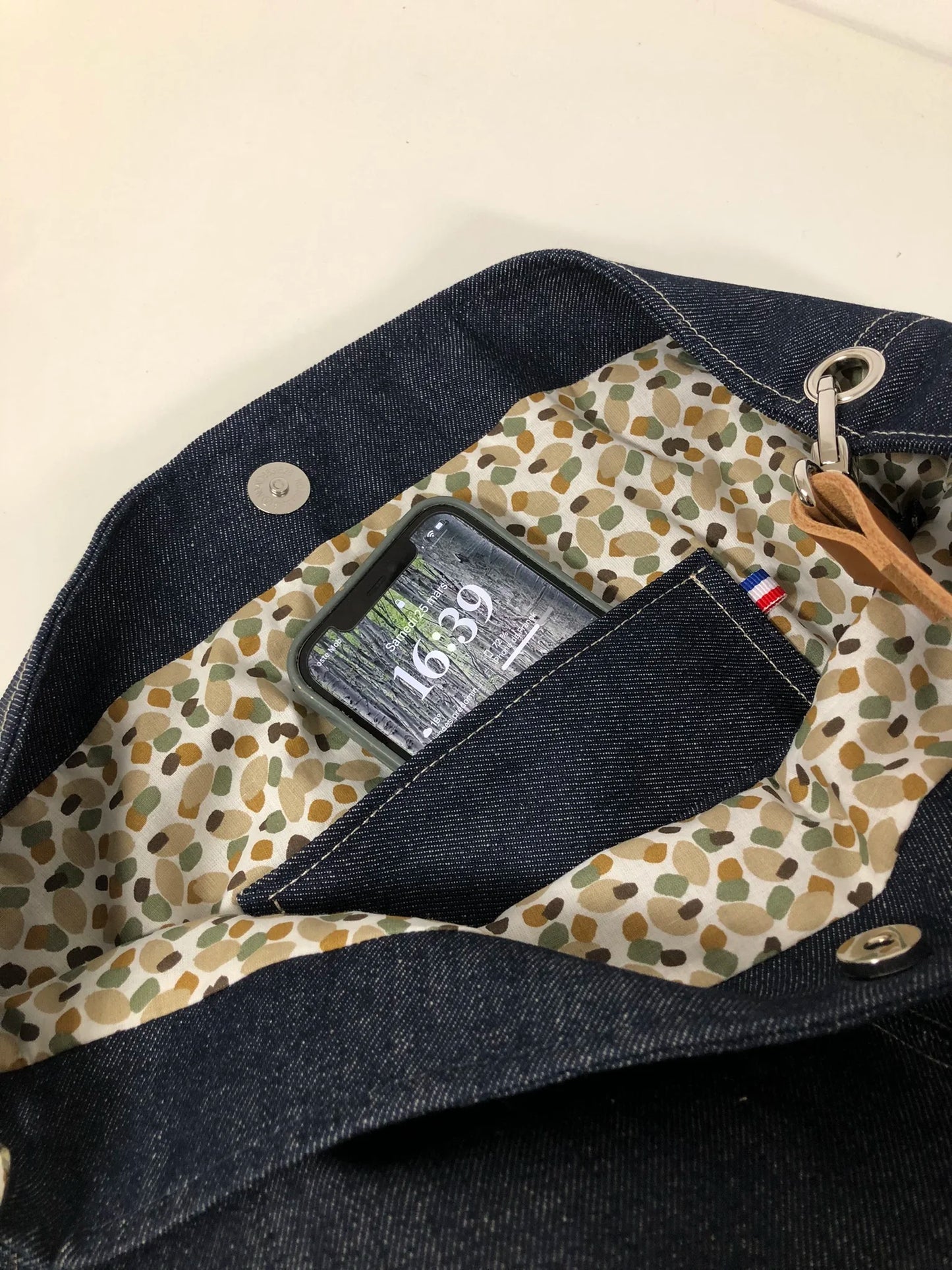 La poche plaquée intérieure du sac hobo en toile denim brut et son anse en cuir .