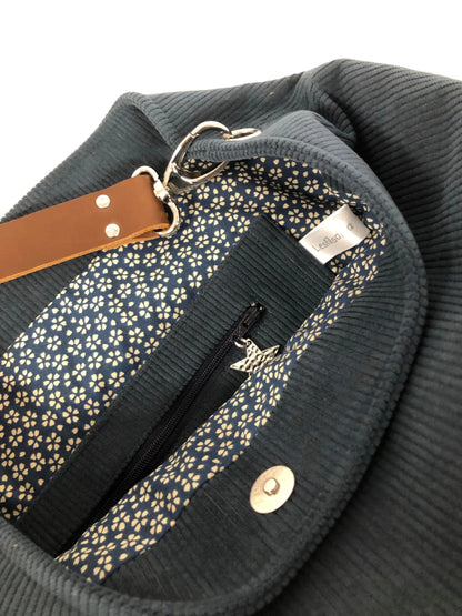 La poche zippée du sac hobo en velours cotelé bleu canard et son anse en cuir marron.