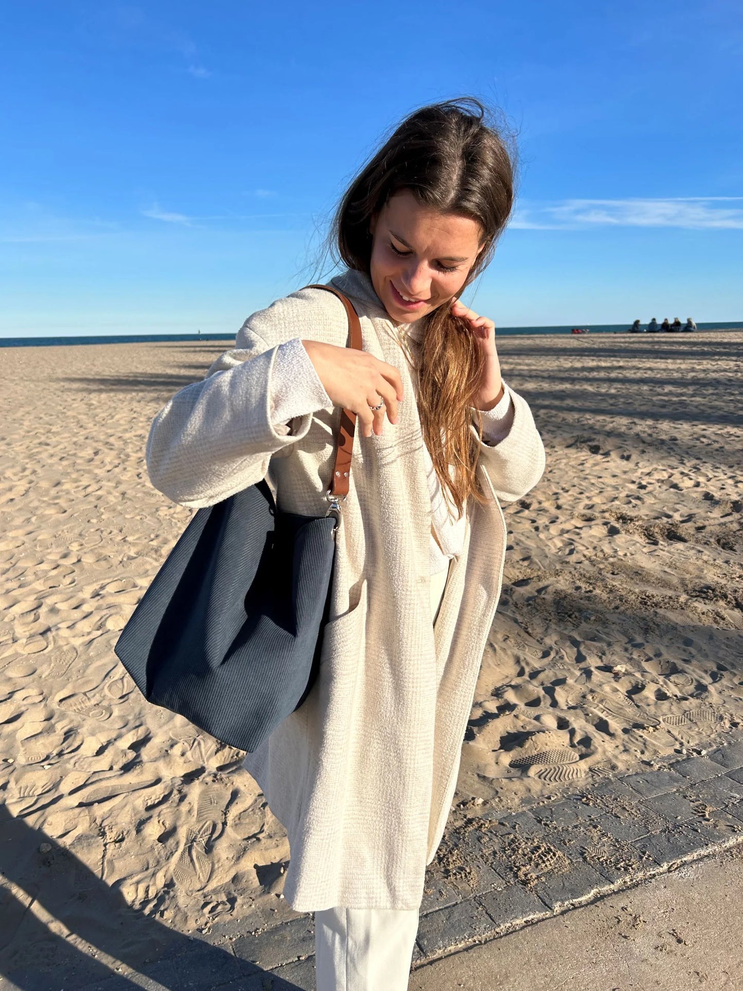 Jeune femme portant le sac hobo en velours cotelé bleu canard et son anse en cuir marron.