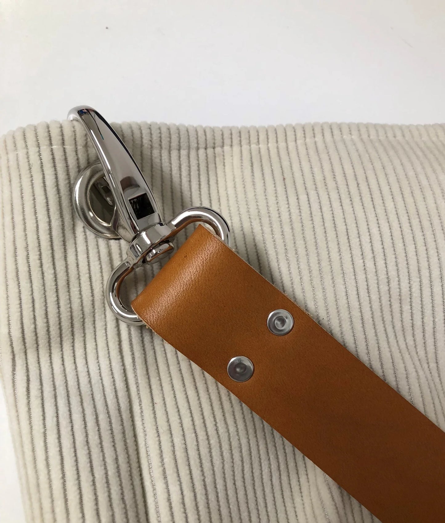 Vue détaillée du sac hobo en velours cotelé ivoire et son anse en cuir fauve.